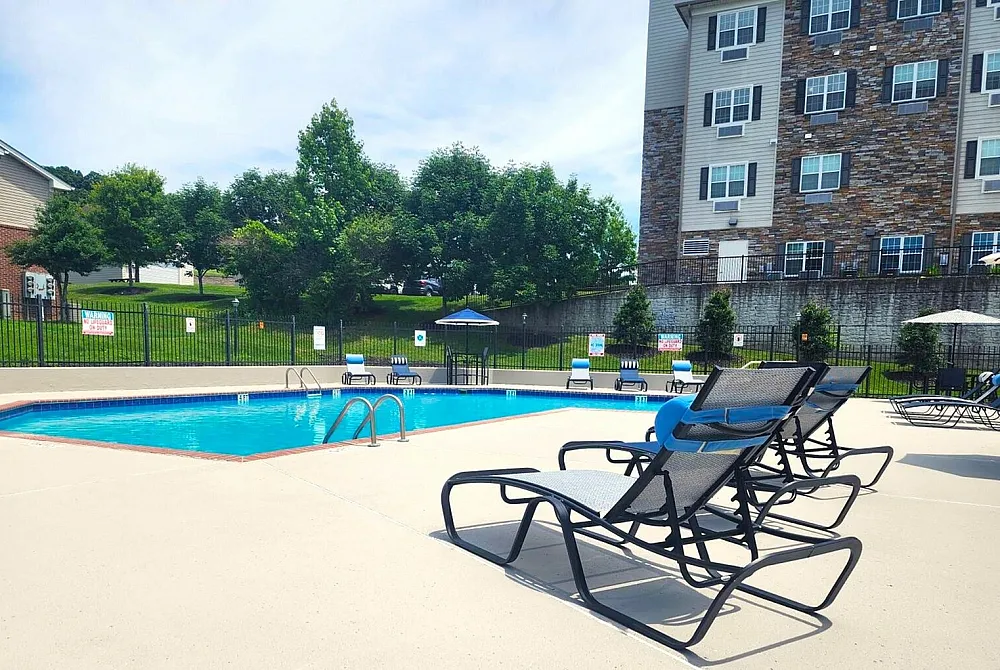 Inviting community pool area with sun loungers and lush greenery, perfect for relaxation and outdoor enjoyment at the residential complex.