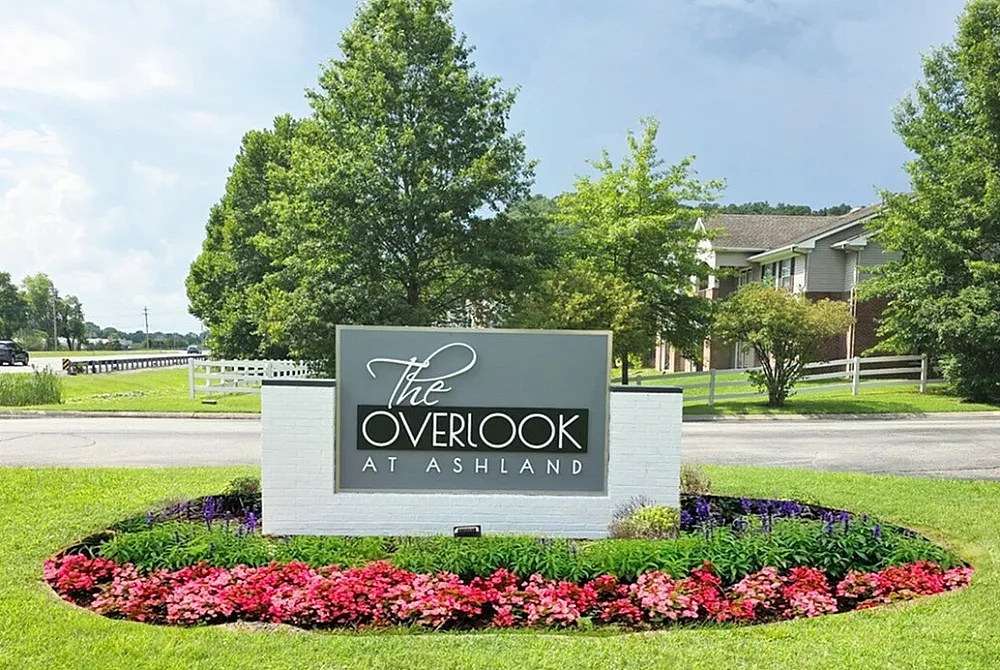 Inviting entrance to The Overlook at Ashland, featuring vibrant landscaping and a welcoming sign under a clear sky.