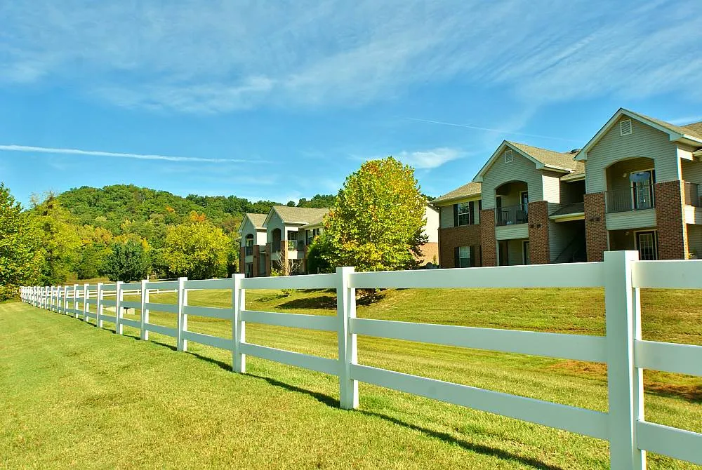 Charming countryside apartments with lush greenery, white fencing, and scenic views of rolling hills.