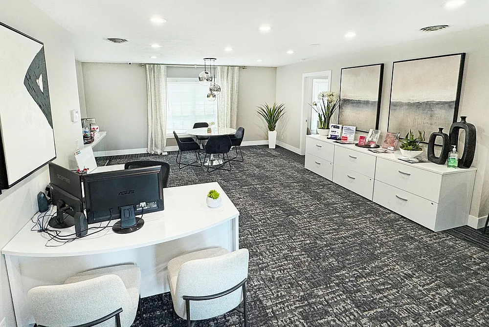 Modern and inviting office space with chic decor, featuring elegant artwork, lush plants, and stylish furniture in a well-lit and spacious setting.