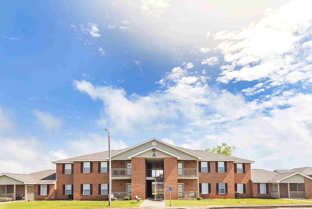 Charming red brick apartment building under a vibrant blue sky, featuring balconies and well-maintained surroundings.