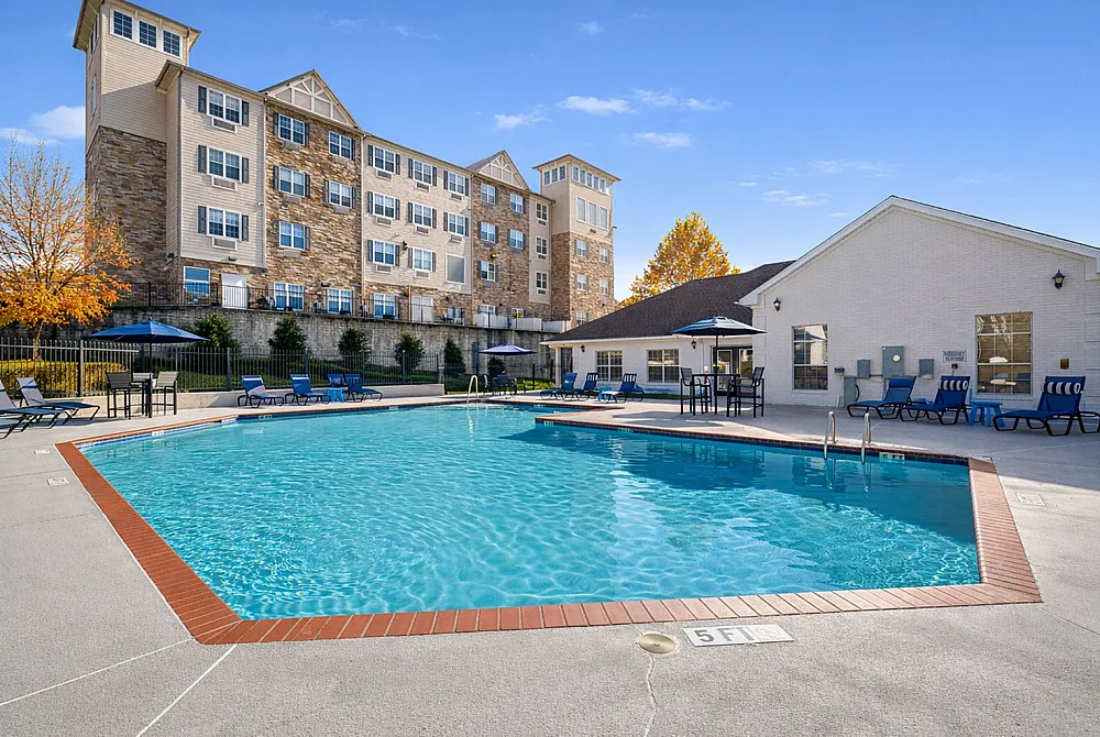 Luxurious apartment complex featuring a stunning outdoor pool with elegant lounge chairs and sun umbrellas, ideal for relaxation and leisure.