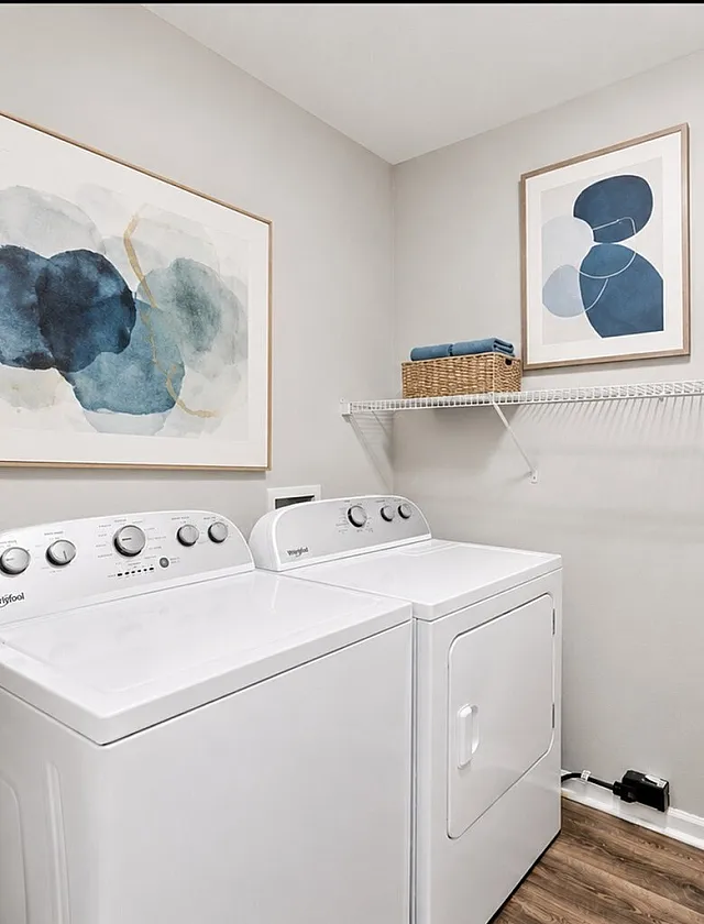 Chic laundry room with modern washer and dryer, featuring contemporary art and practical shelving for a stylish, efficient space.