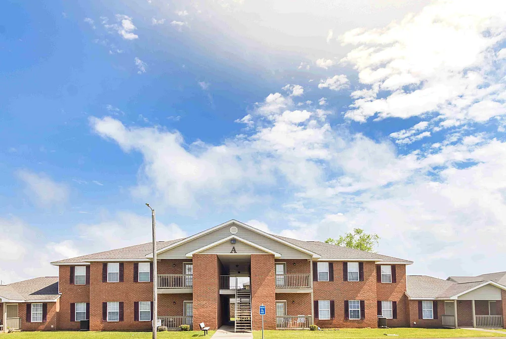Charming brick apartment complex with spacious balconies set against a bright blue sky.