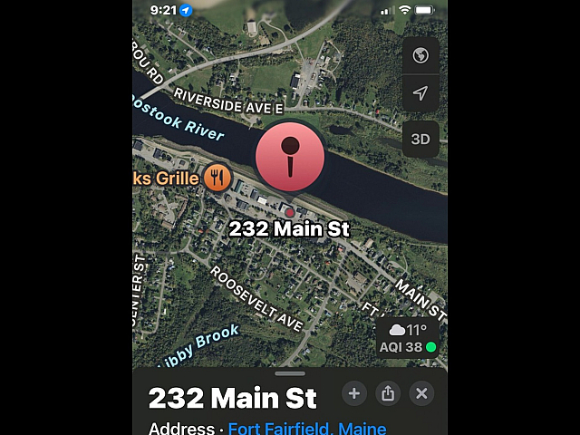 Aerial view of 232 Main St in Fort Fairfield, Maine, featuring scenic riverside location with lush greenery and nearby amenities.