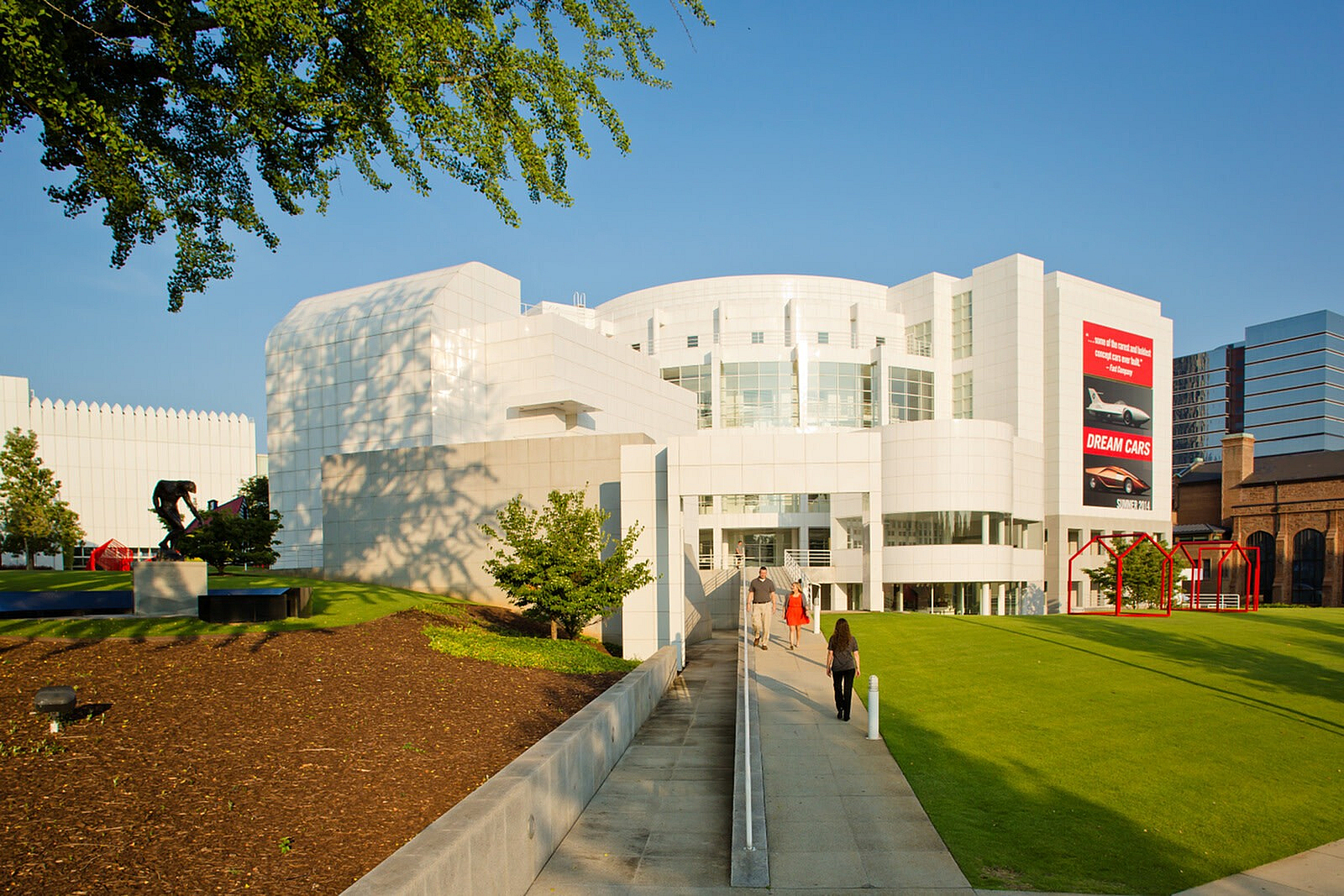 Stunning modern architectural building with sleek white facade, surrounded by lush greenery and clear blue skies.