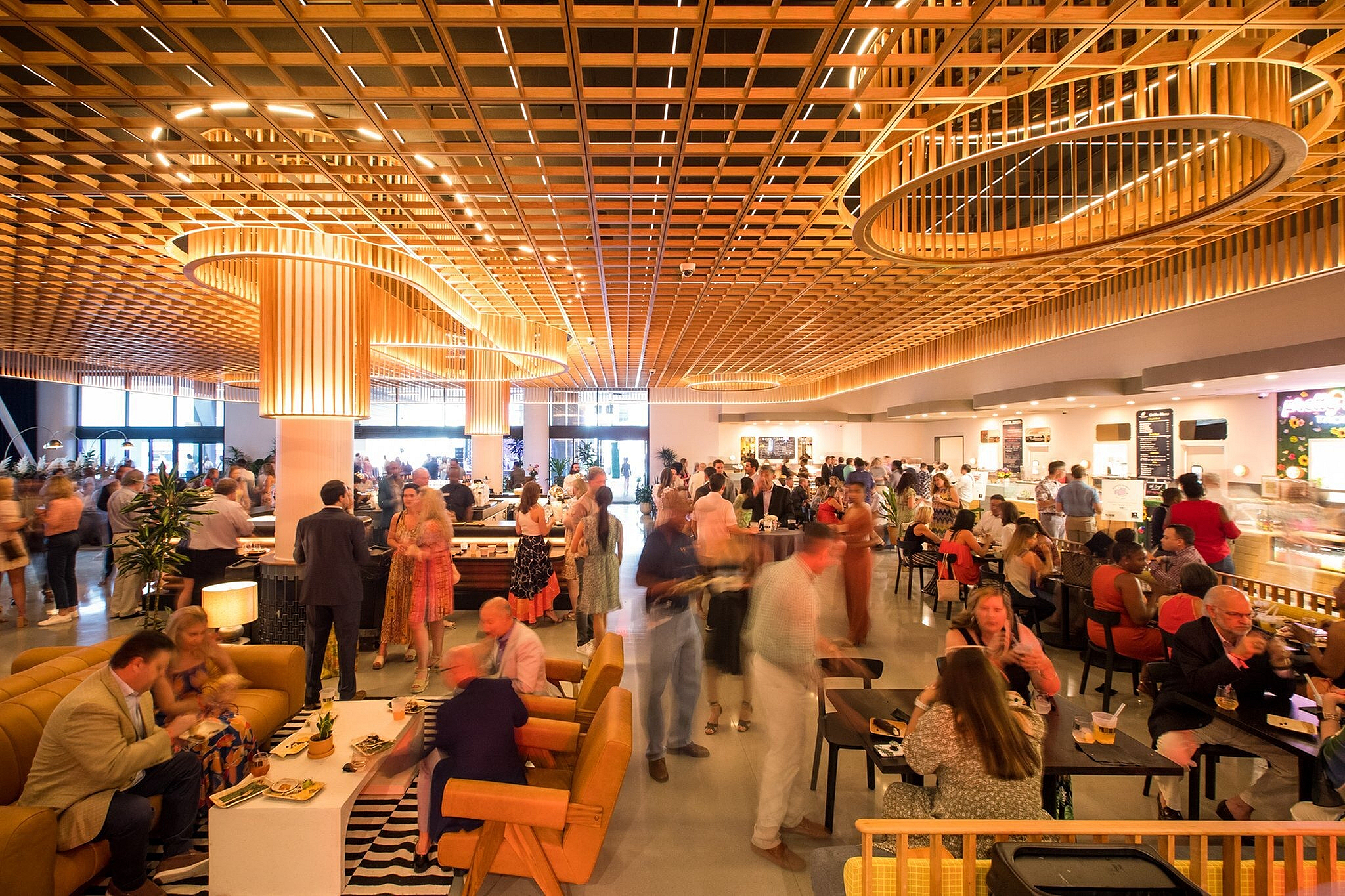 Vibrant event space with modern decor, featuring a dynamic crowd enjoying food and conversation under artistic lighting.