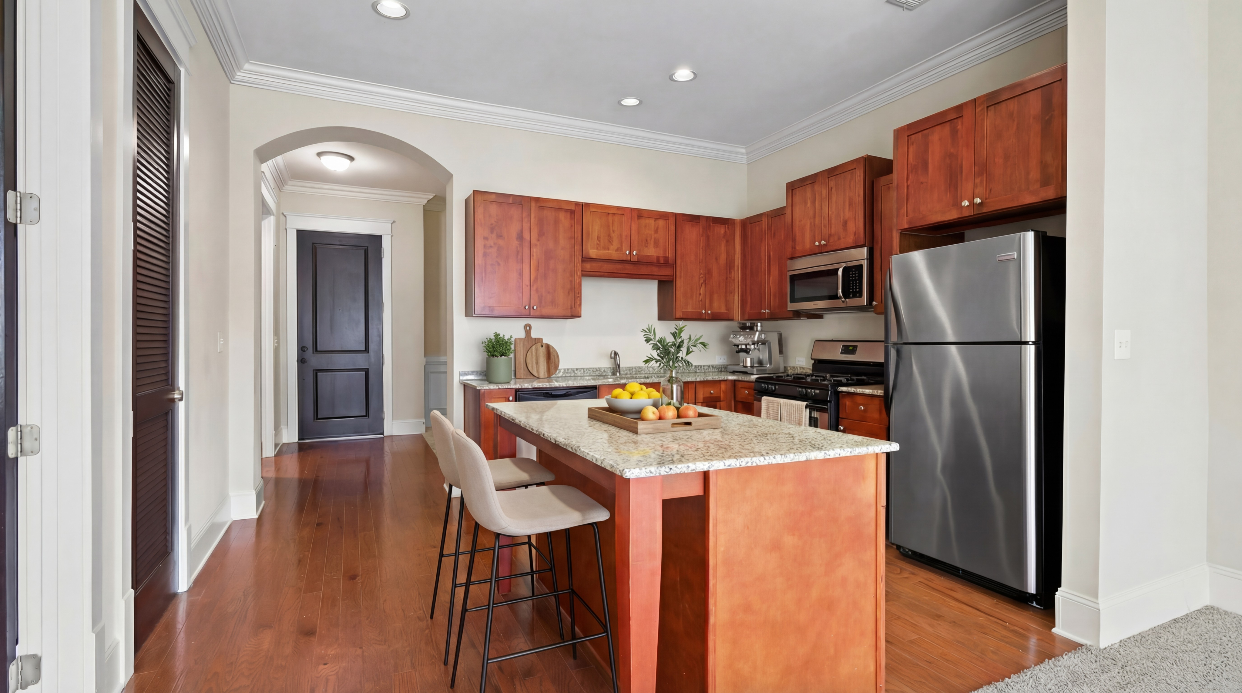 Modern kitchen with rich wooden cabinets, stainless steel appliances, and a sleek granite island with bar seating.