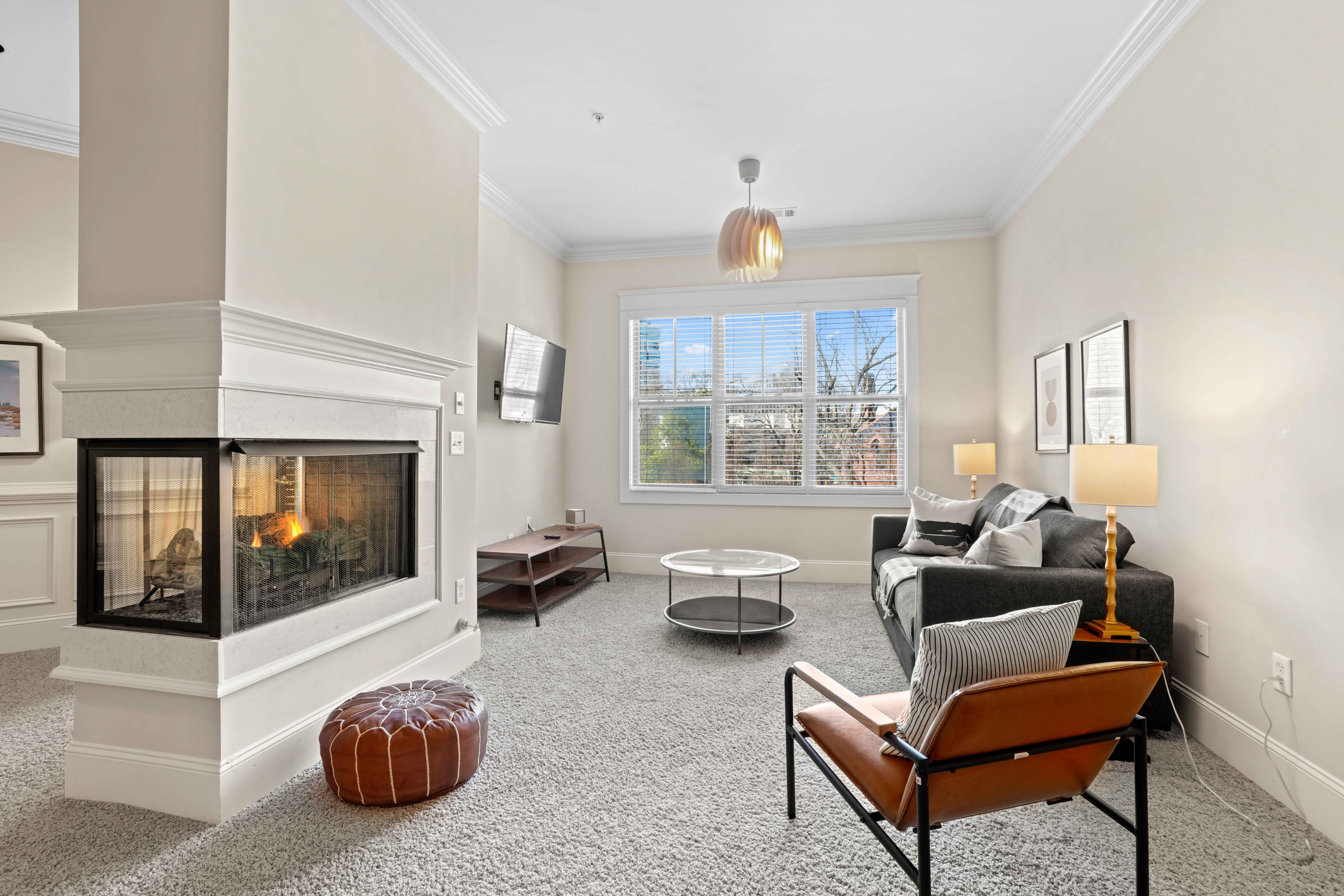 Bright and cozy living room with a stylish fireplace, modern furniture, and large windows offering natural light.