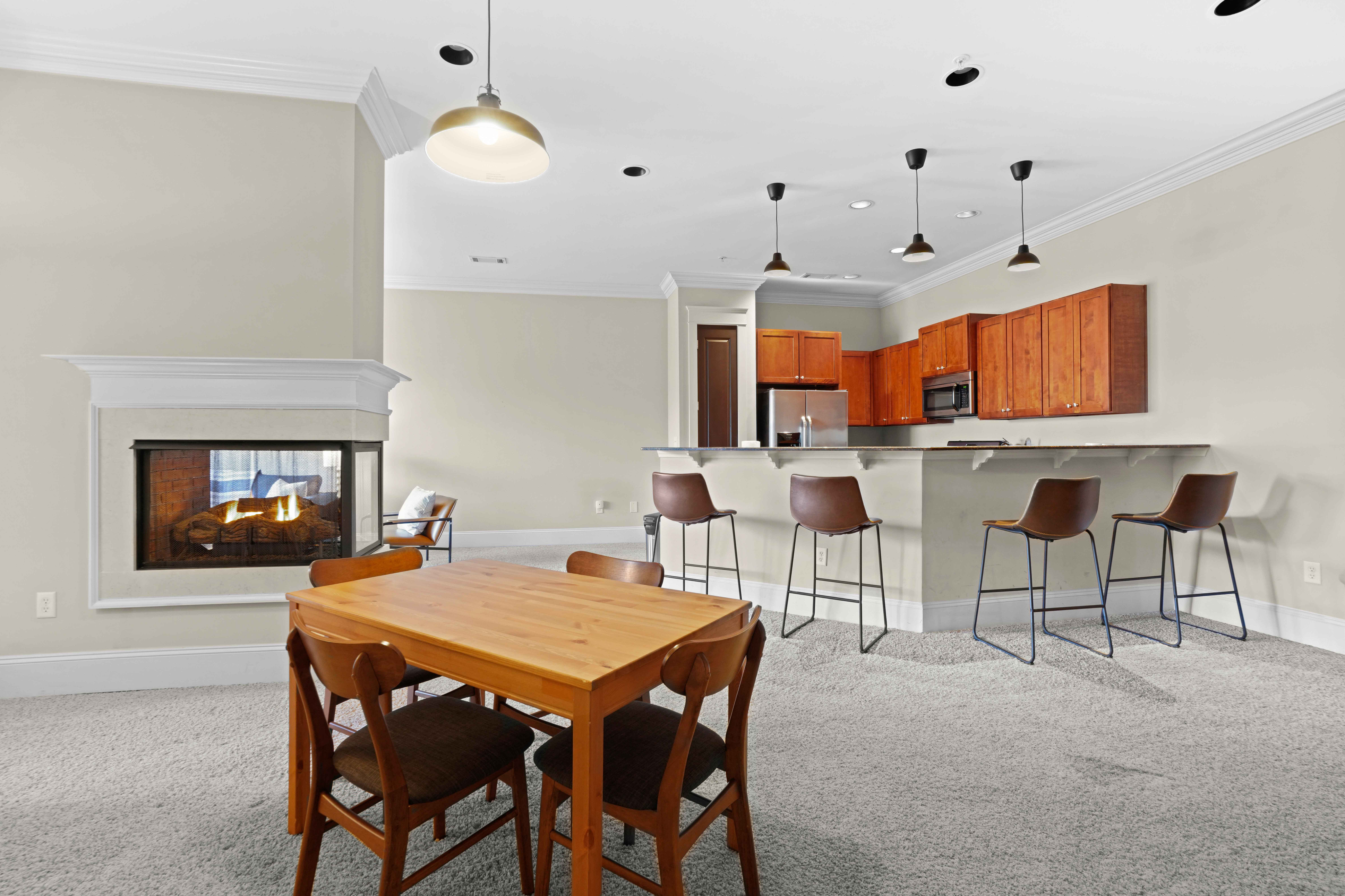 Modern open-concept kitchen and dining area with cozy fireplace and stylish bar seating.