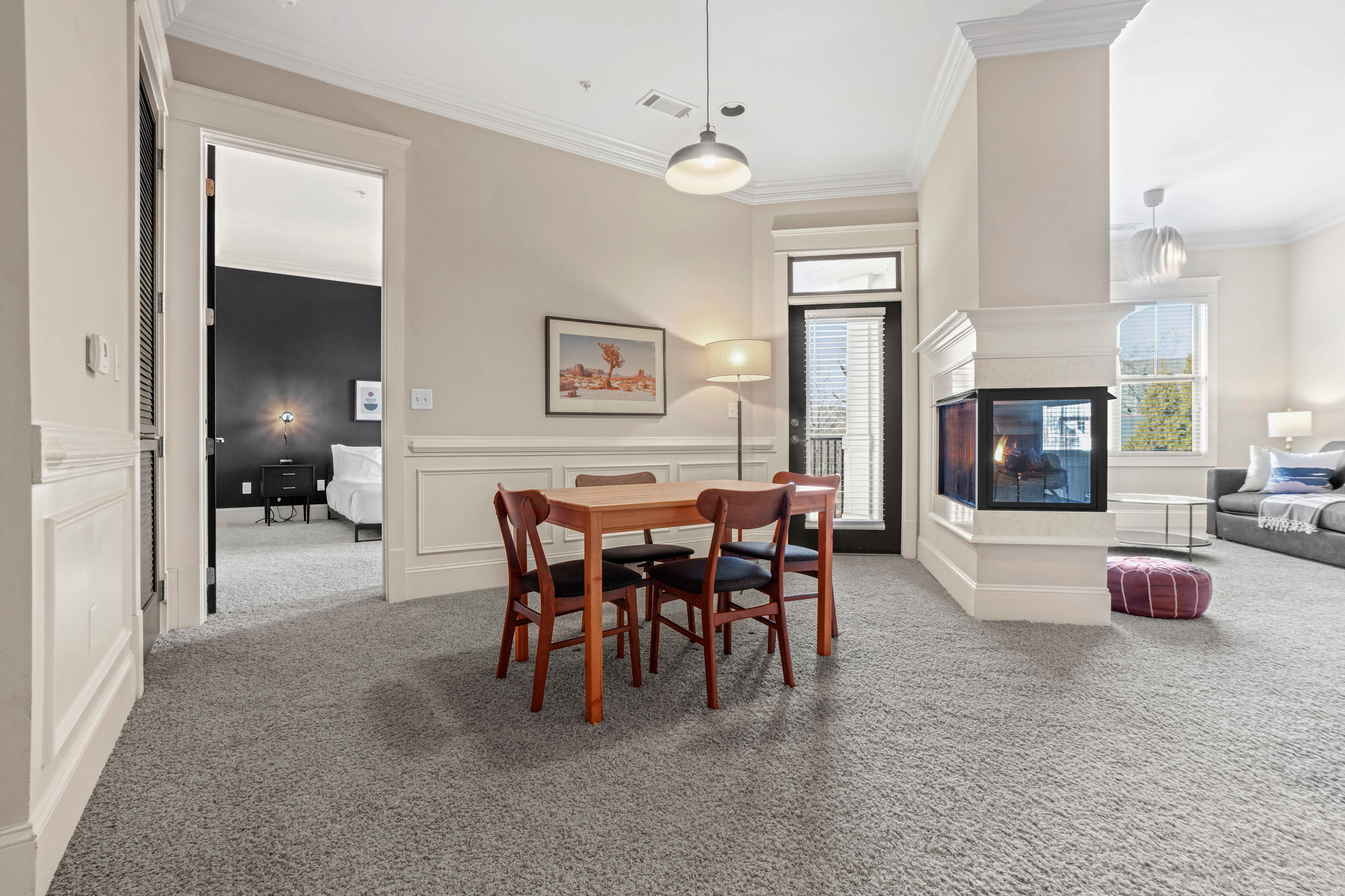 Bright, open living space featuring a cozy dining area, modern fireplace, and elegant seating in a spacious apartment.