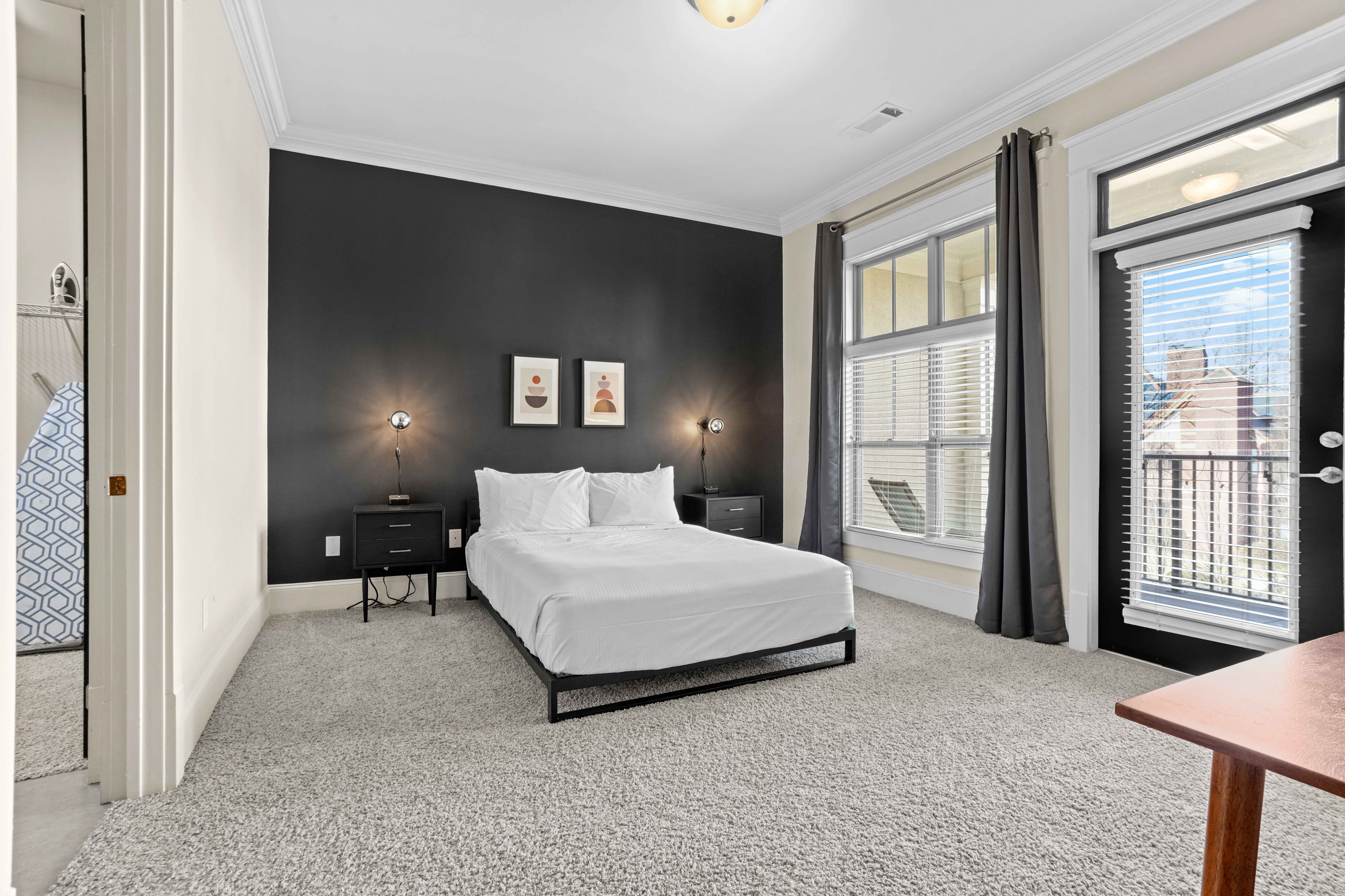 Elegant bedroom featuring modern decor, plush carpeting, large windows with natural light, and minimalist black and white design.