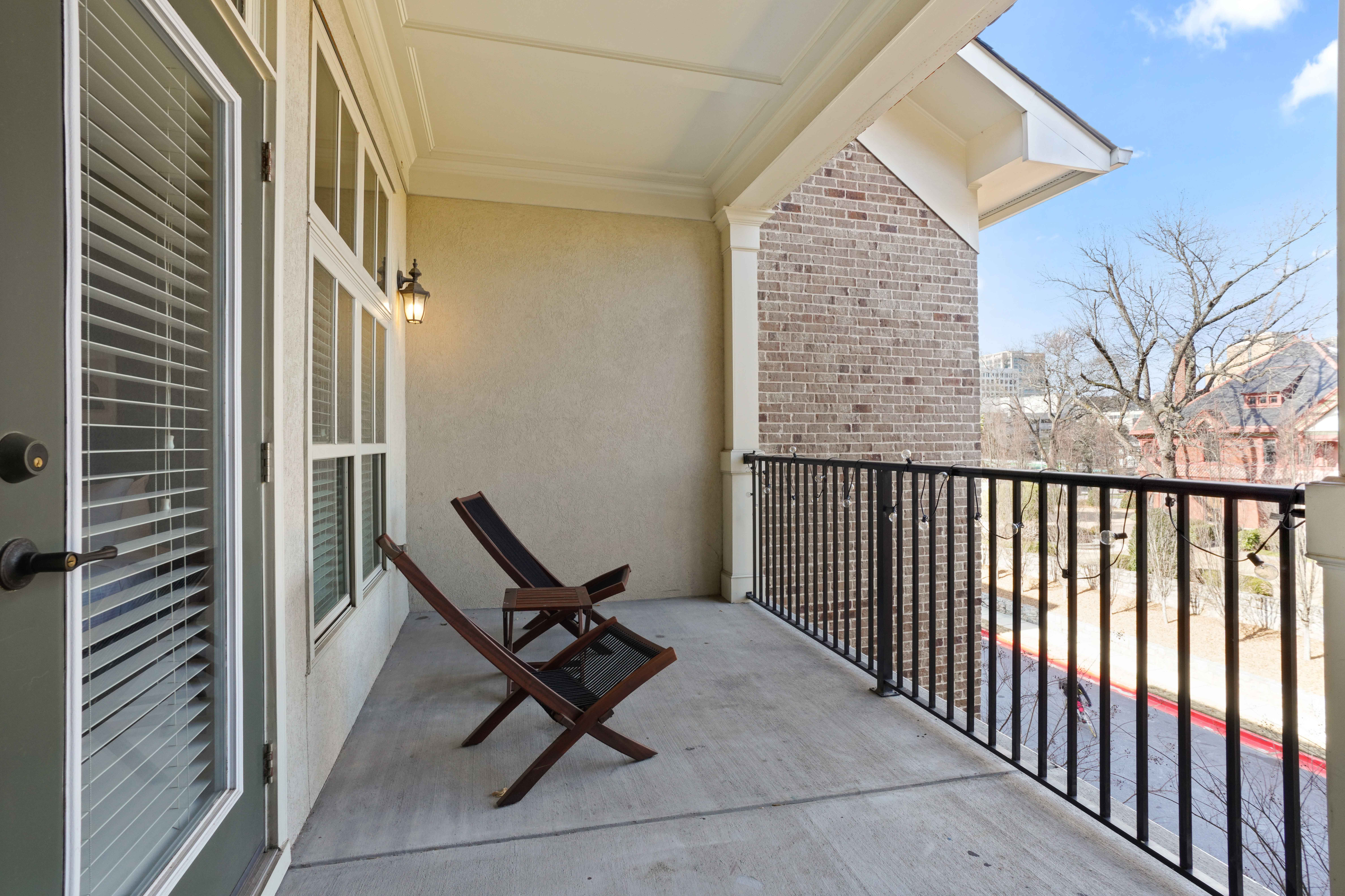 Charming apartment balcony with sleek railing, stylish outdoor seating, and a scenic neighborhood view.