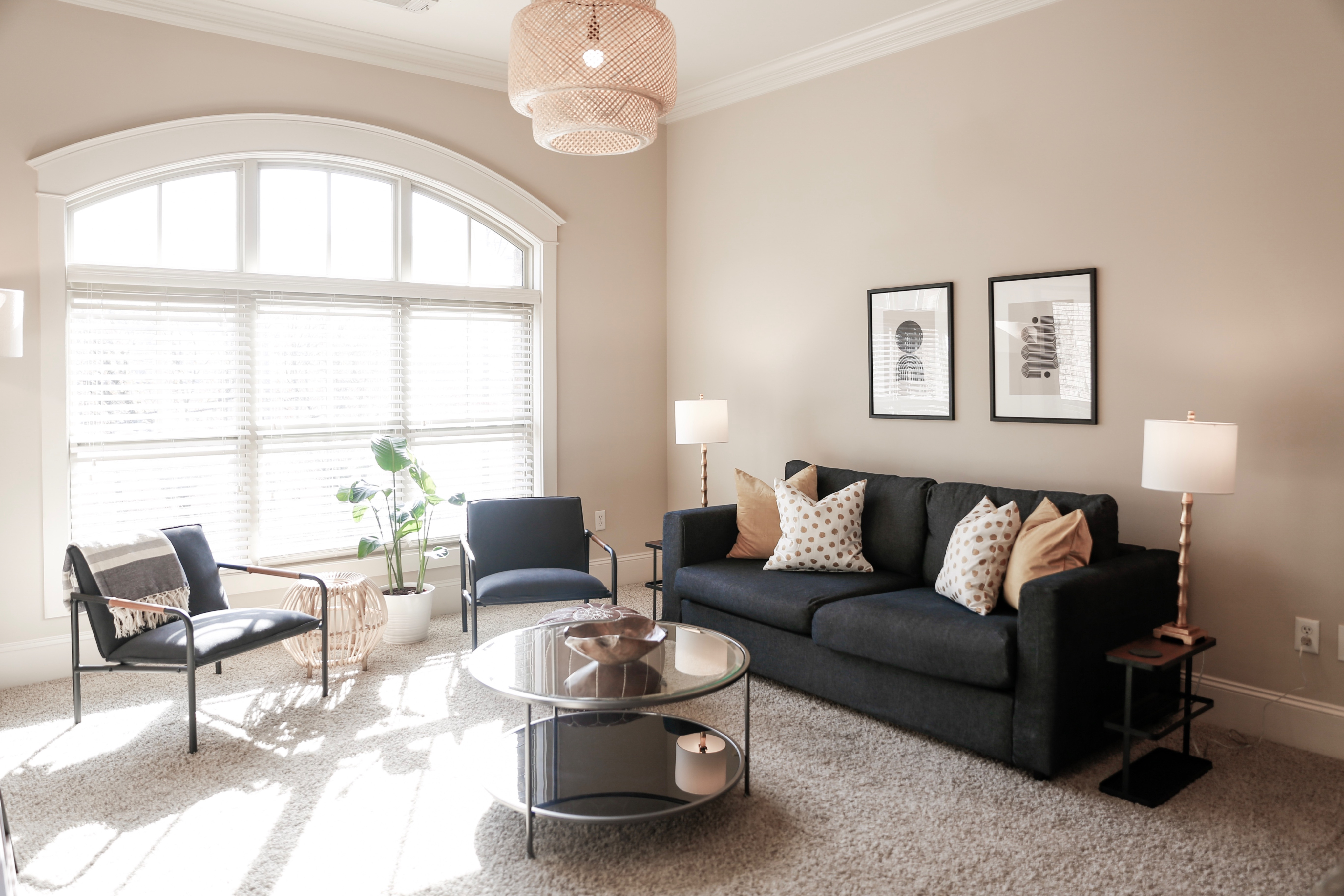 Bright and inviting living room with a modern sofa, stylish armchairs, and large windows flooding the space with natural light.