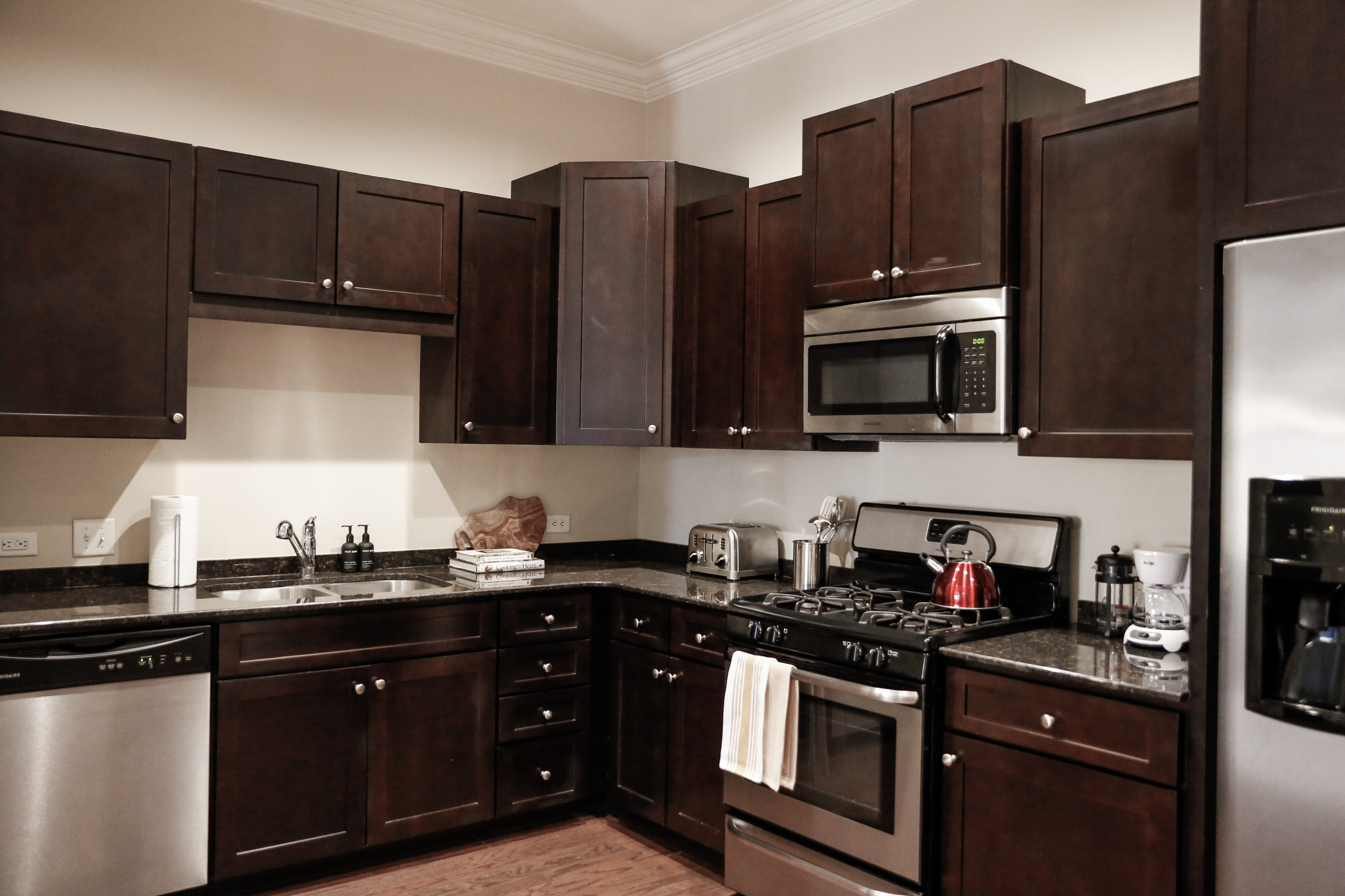 Modern kitchen with dark wooden cabinets, stainless steel appliances, and sleek granite countertops.