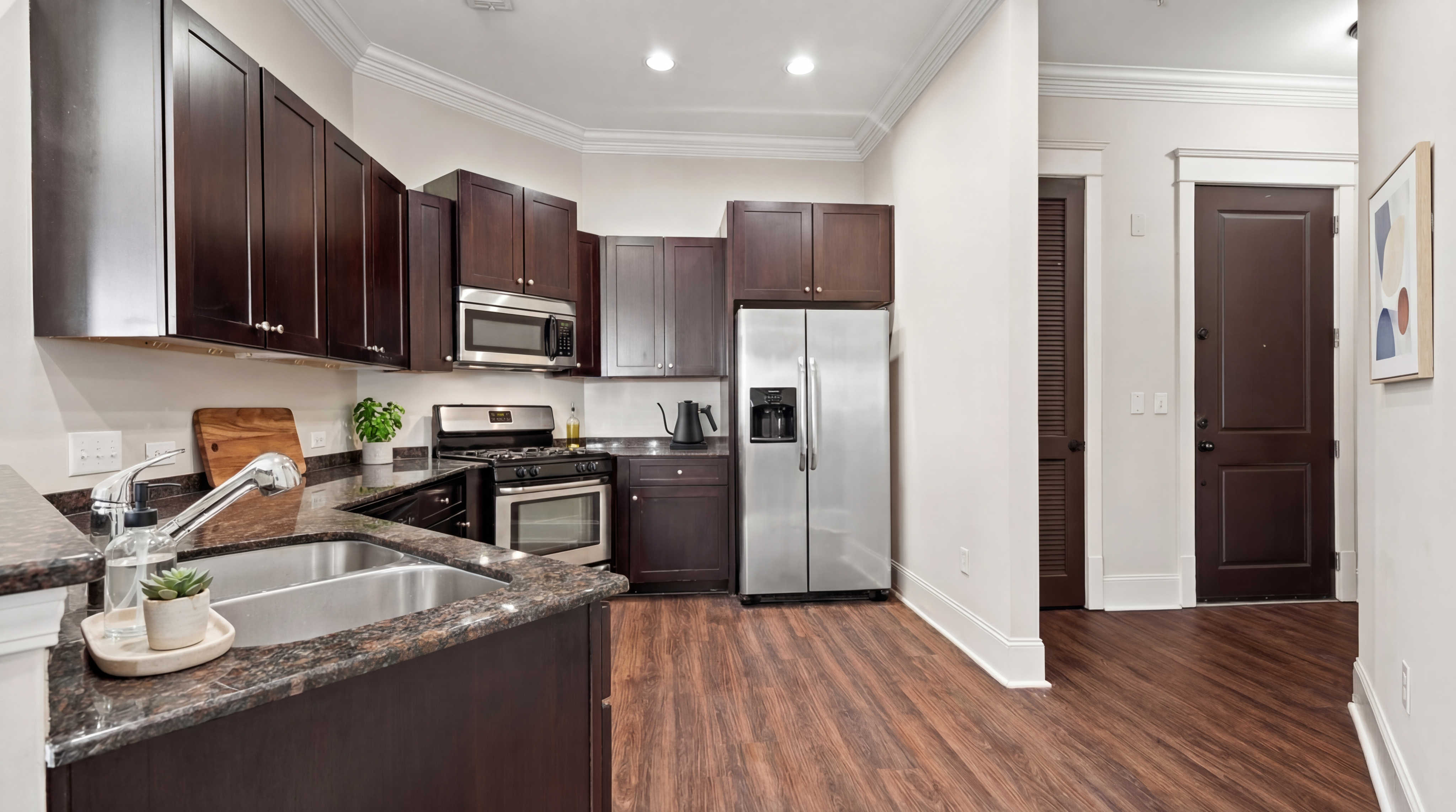 Modern kitchen with dark wood cabinets, stainless steel appliances, and elegant granite countertops offering a stylish and functional space.