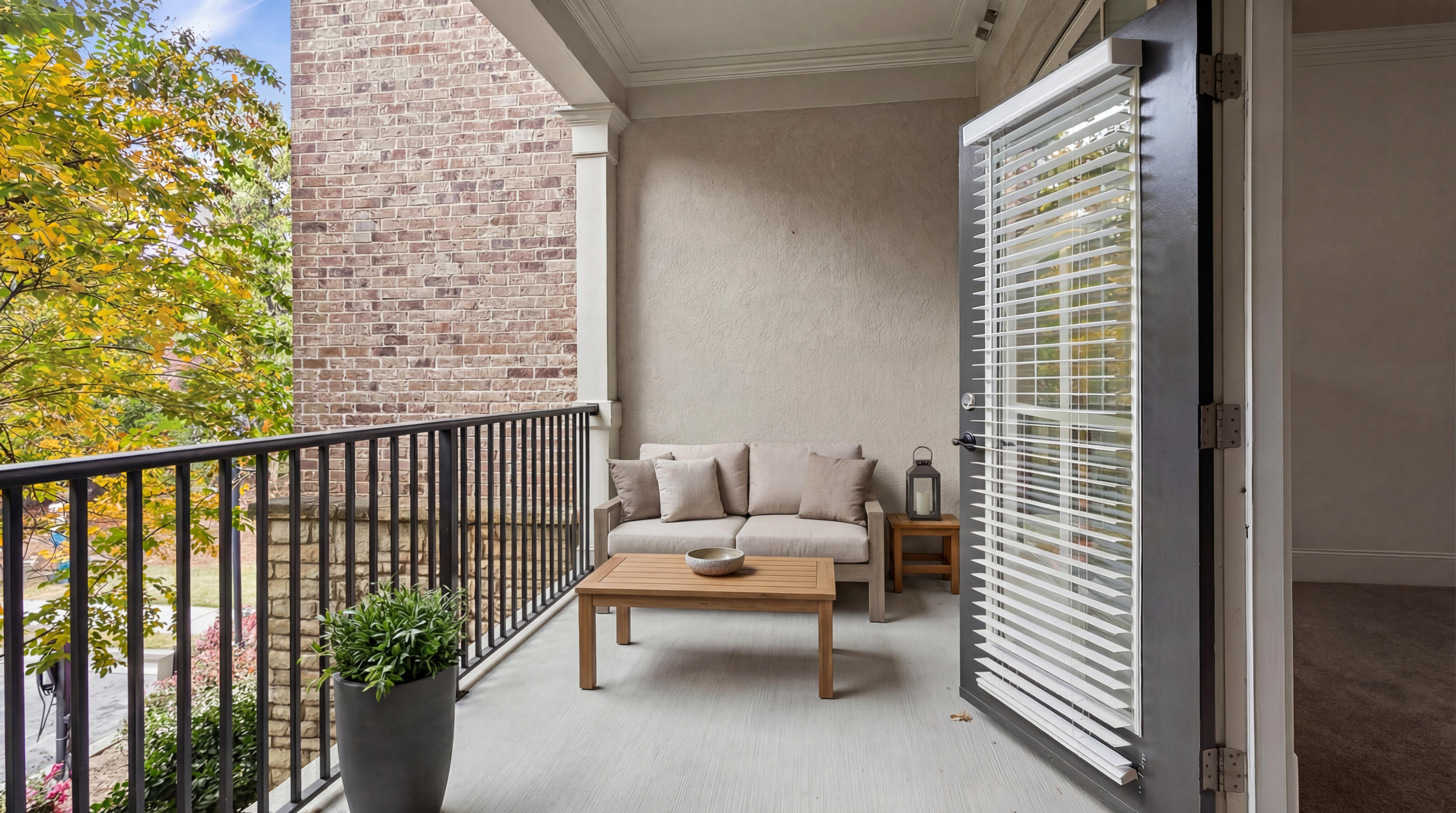 Charming balcony retreat with cozy seating, overlooking vibrant autumn foliage and rustic brick wall.