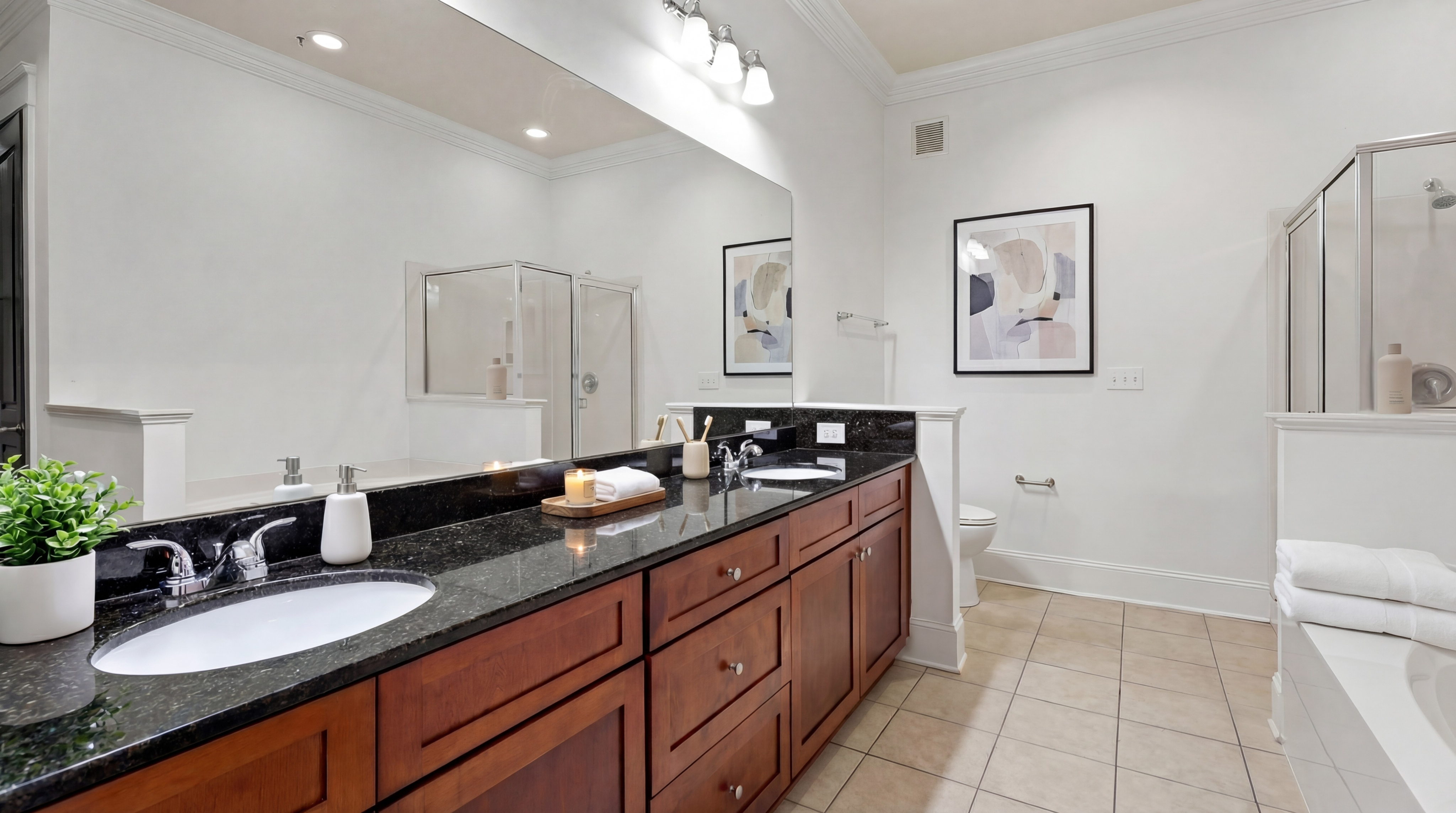 Luxurious bathroom with dual sinks, modern fixtures, elegant artwork, and a glass-enclosed shower.