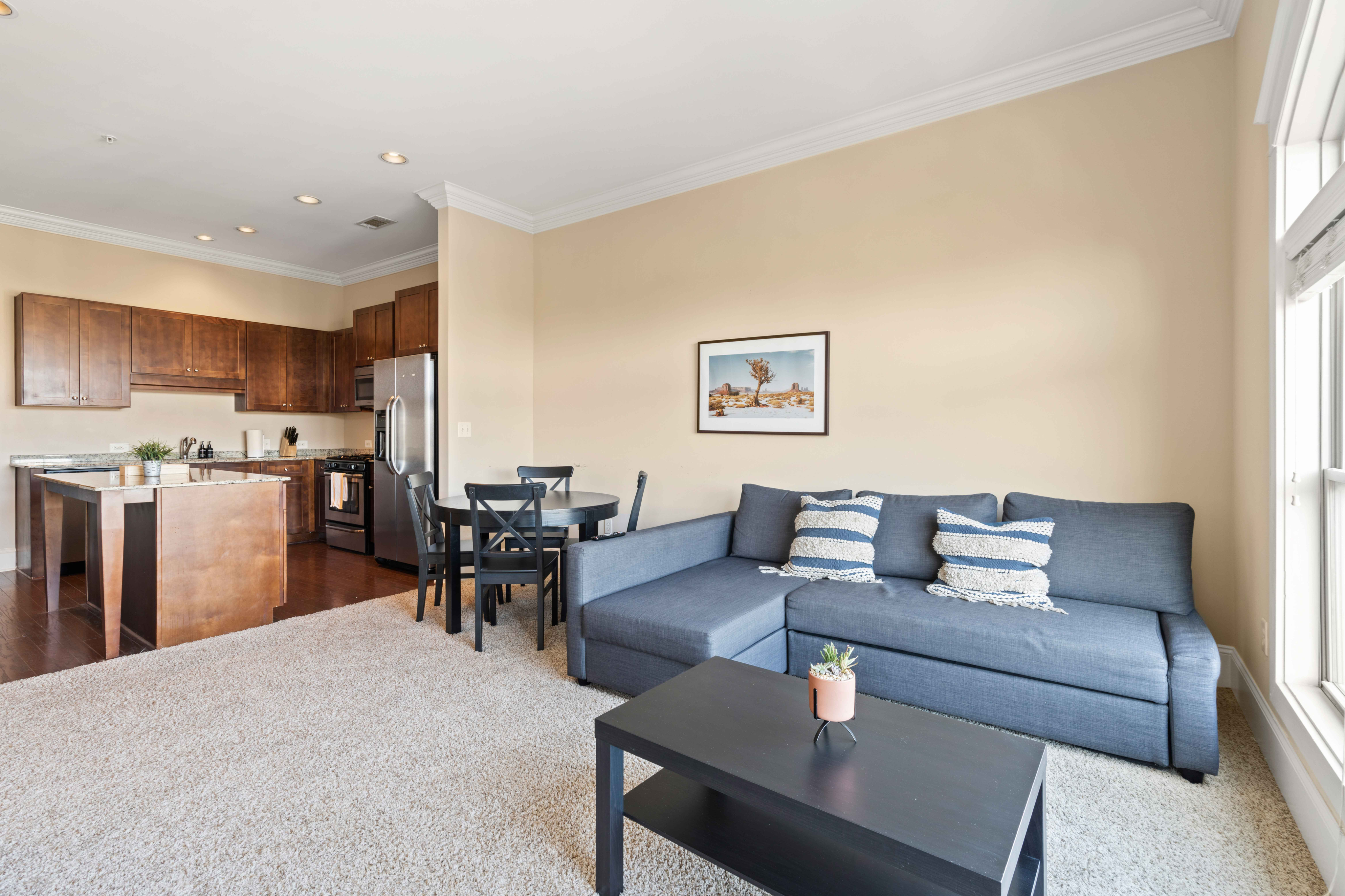 Inviting open-plan living space with contemporary kitchen, cozy dining area, and plush sectional sofa, perfect for elegant and comfortable living.