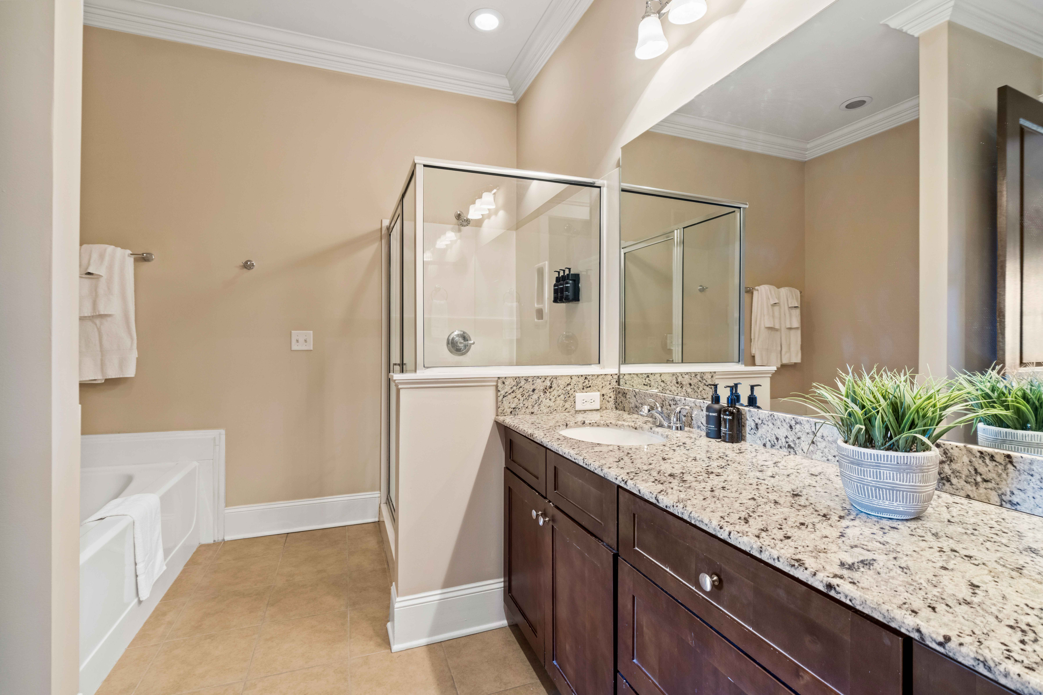 Elegant bathroom featuring a granite countertop, modern fixtures, and a spacious glass-enclosed shower.