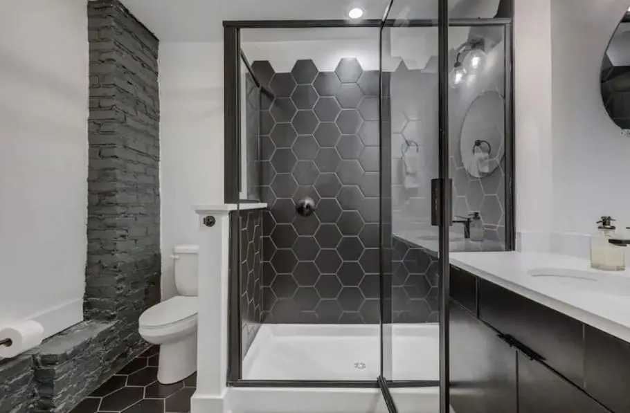 Modern bathroom with sleek black hexagonal tiles and elegant glass shower enclosure.