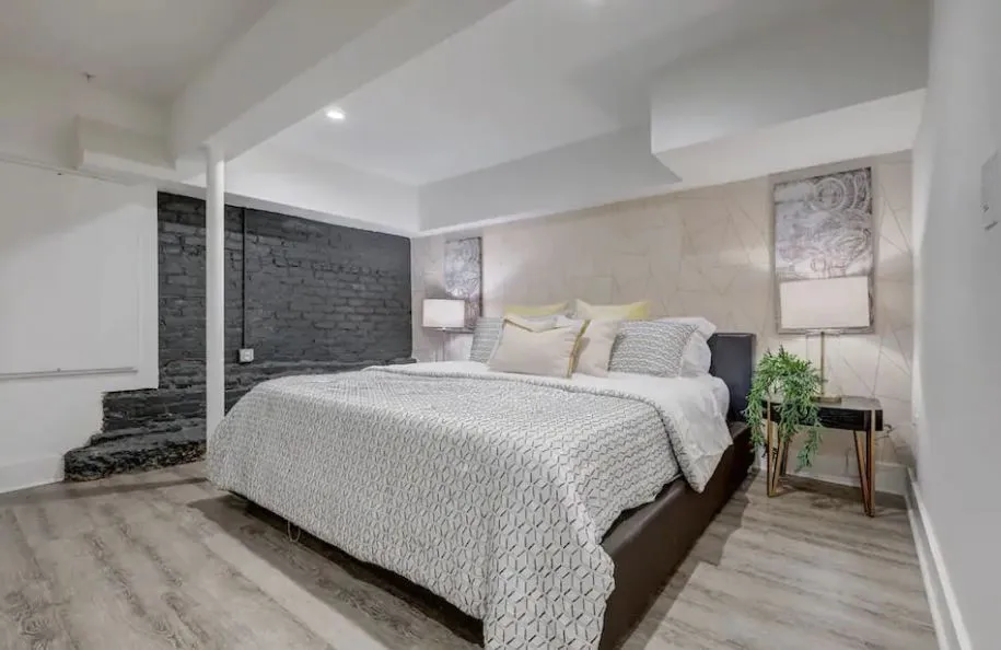 Chic and cozy bedroom with contemporary design, featuring a comfortable bed, stylish brick accent wall, and warm ambient lighting.