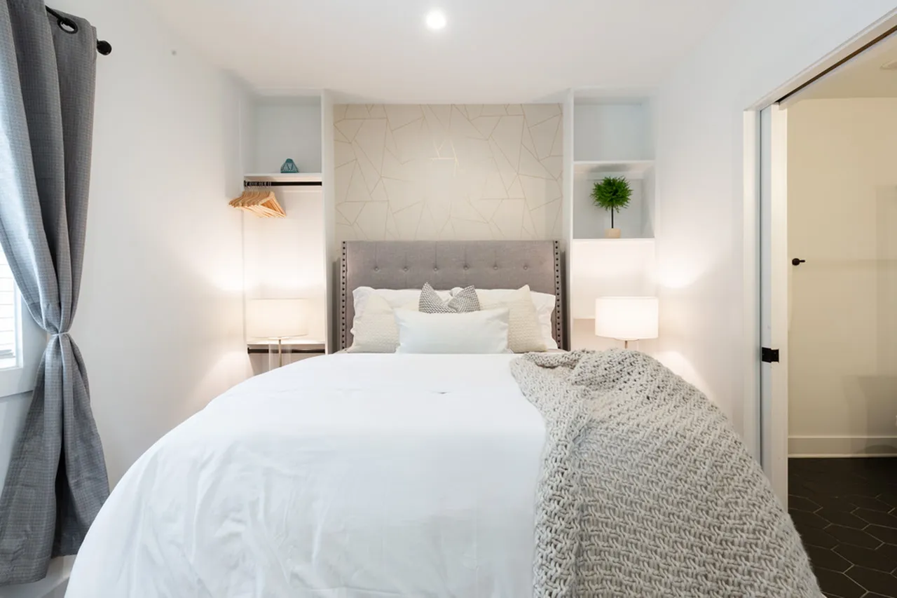 Cozy bedroom with plush bed, elegant decor, and natural light enhancing a serene ambiance.