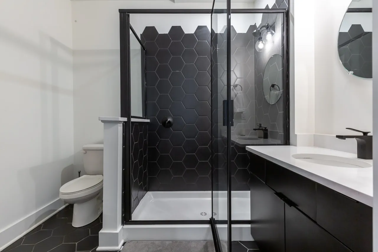 Elegant bathroom with sleek black hexagonal tiles and modern glass shower enclosure.