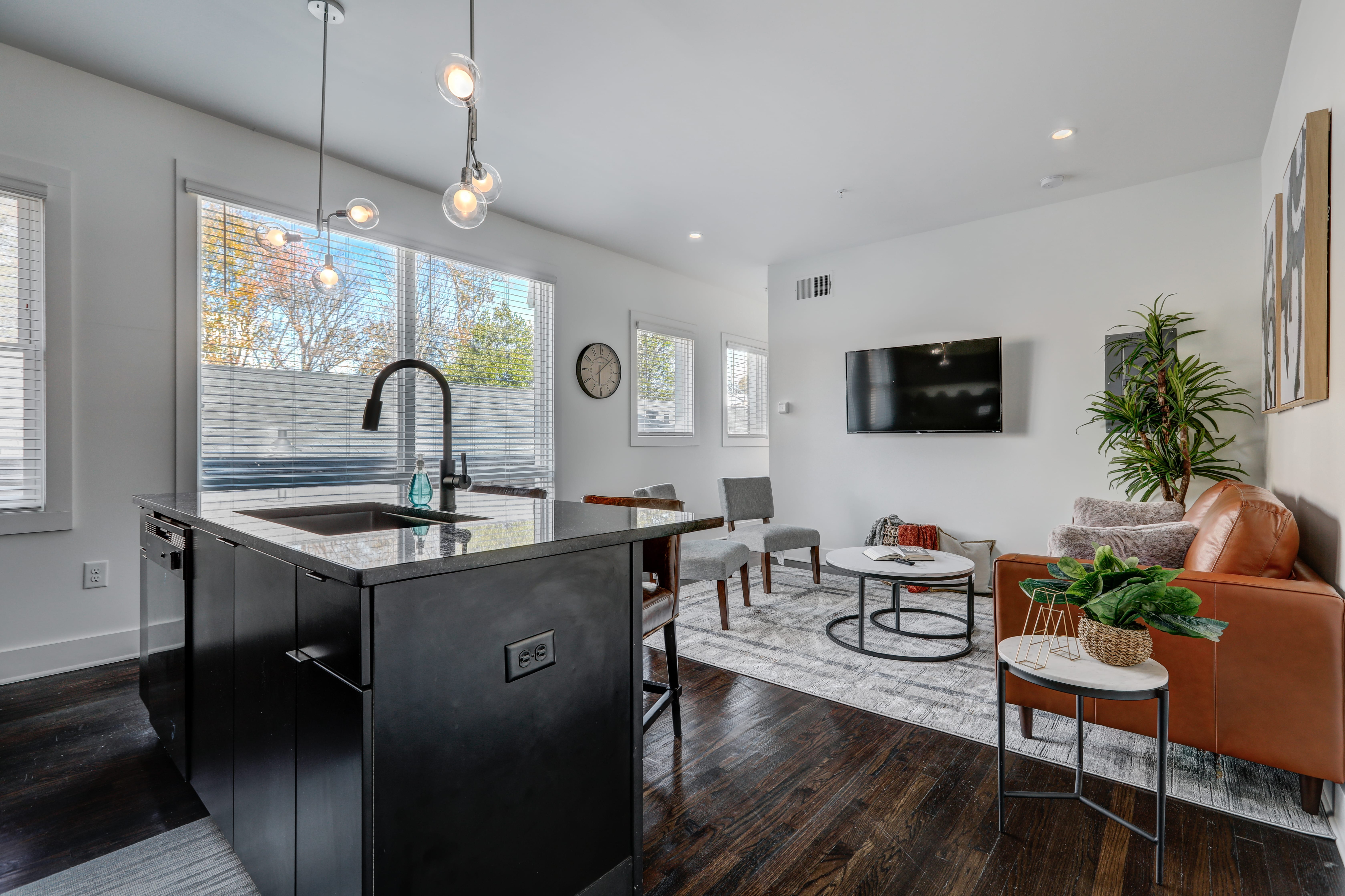 Modern open-concept living area with stylish kitchen island, sleek fixtures, chic seating, and abundant natural light.