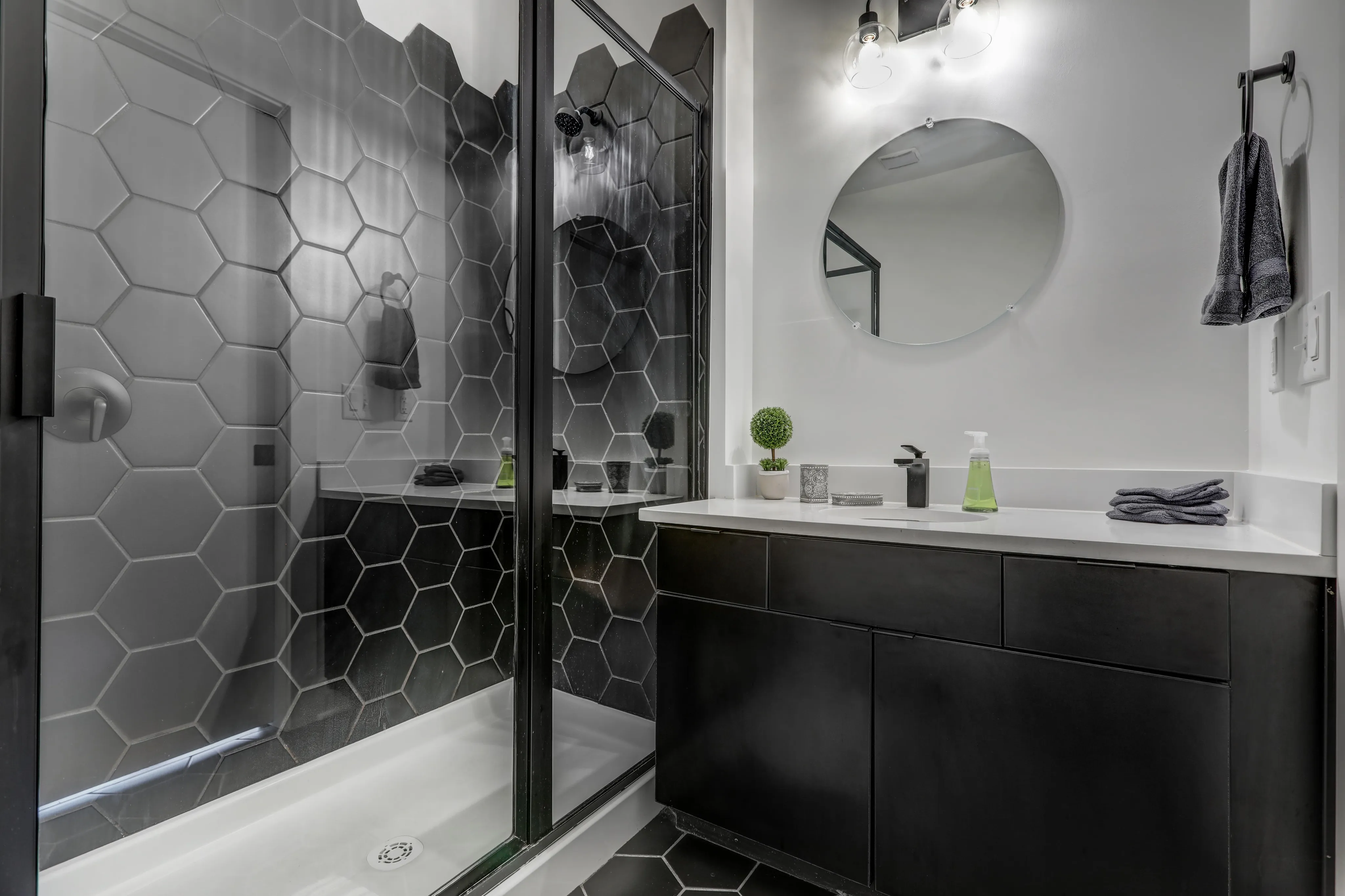 Sleek modern bathroom with hexagonal tile design, glass shower door, and contemporary vanity.