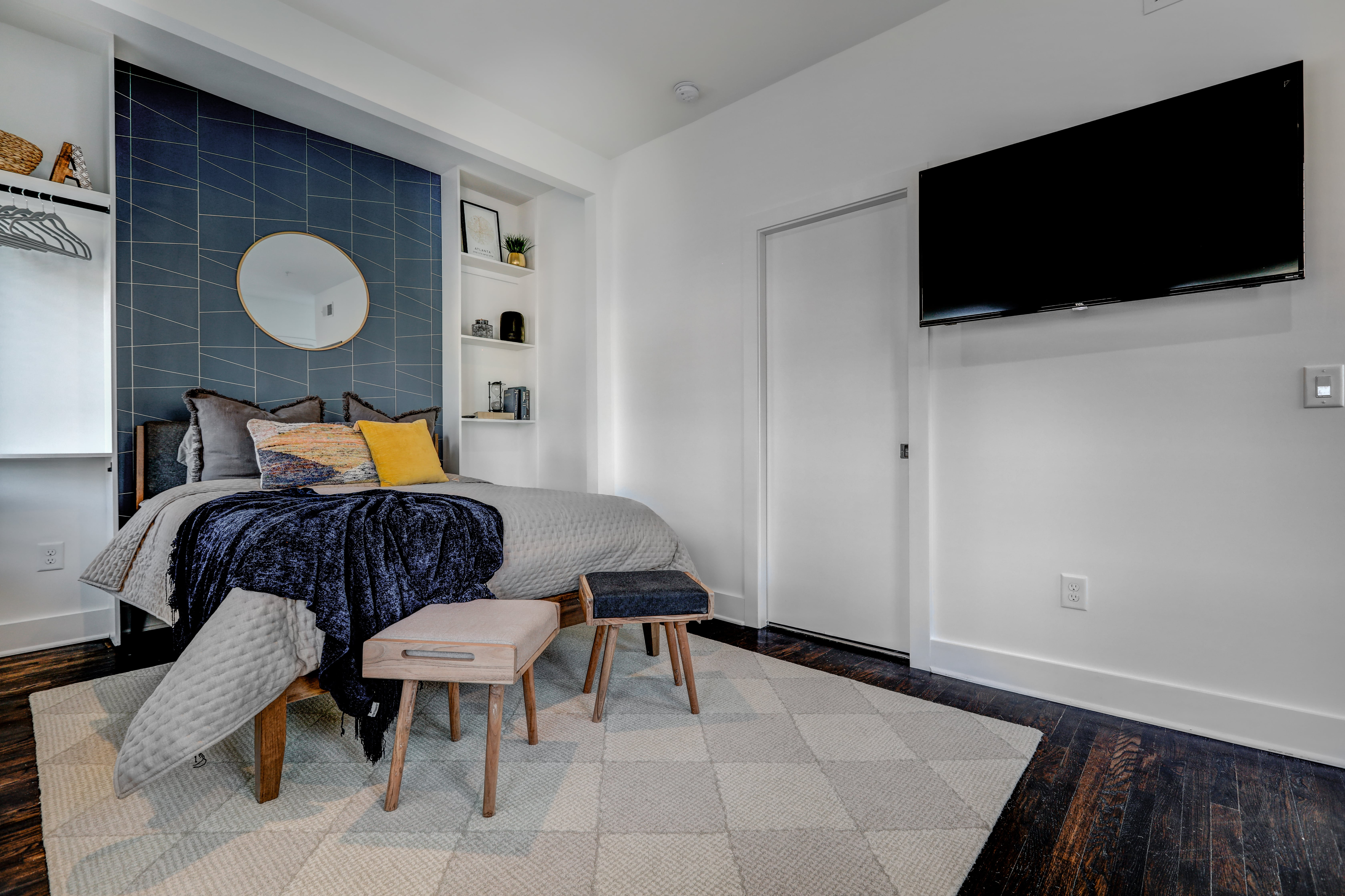 Modern bedroom with plush bedding, elegant blue accent wall, and built-in shelves for a cozy, stylish retreat.