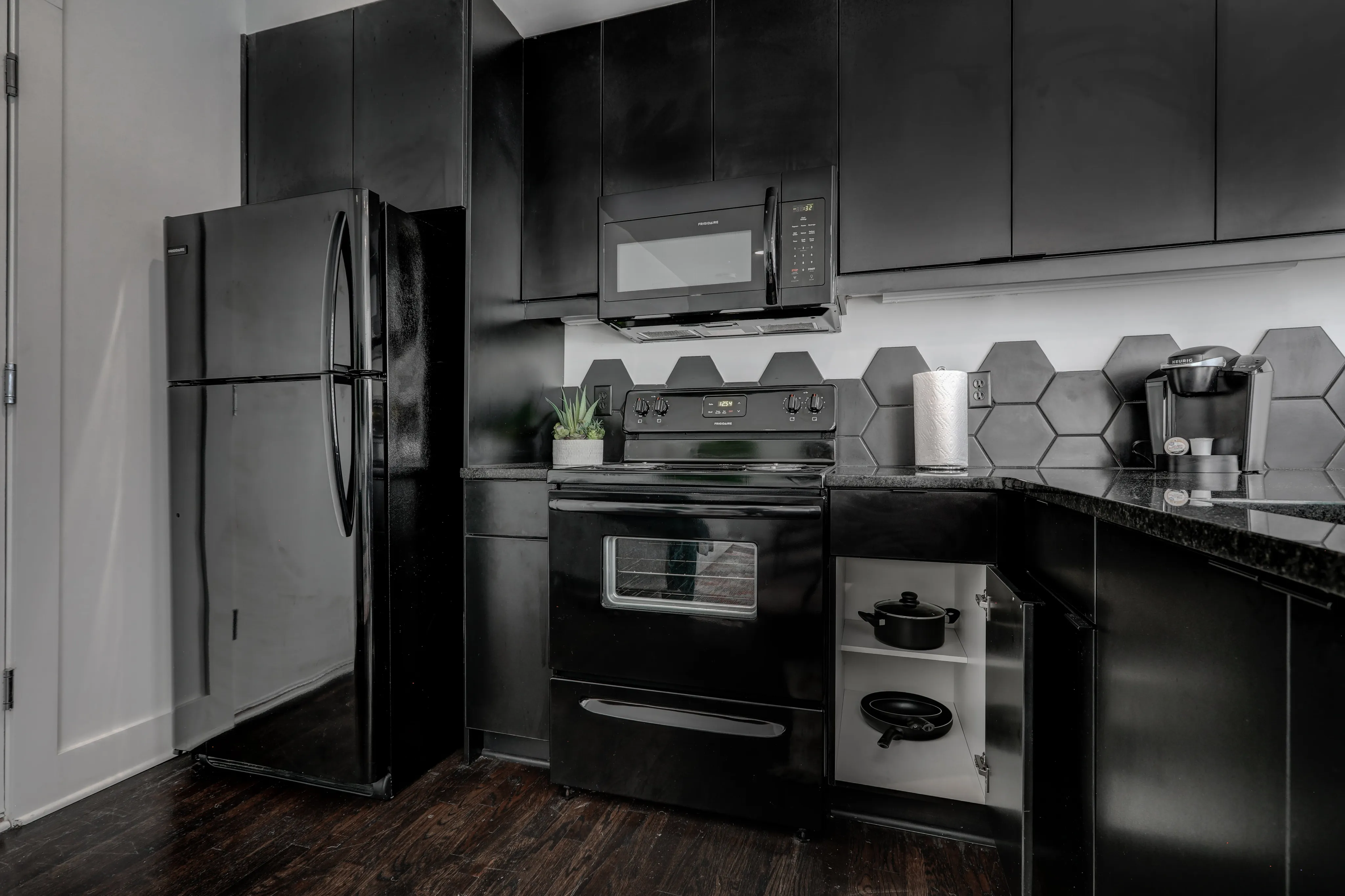 Modern kitchen with sleek black appliances, hexagonal tile backsplash, and elegant cabinetry.