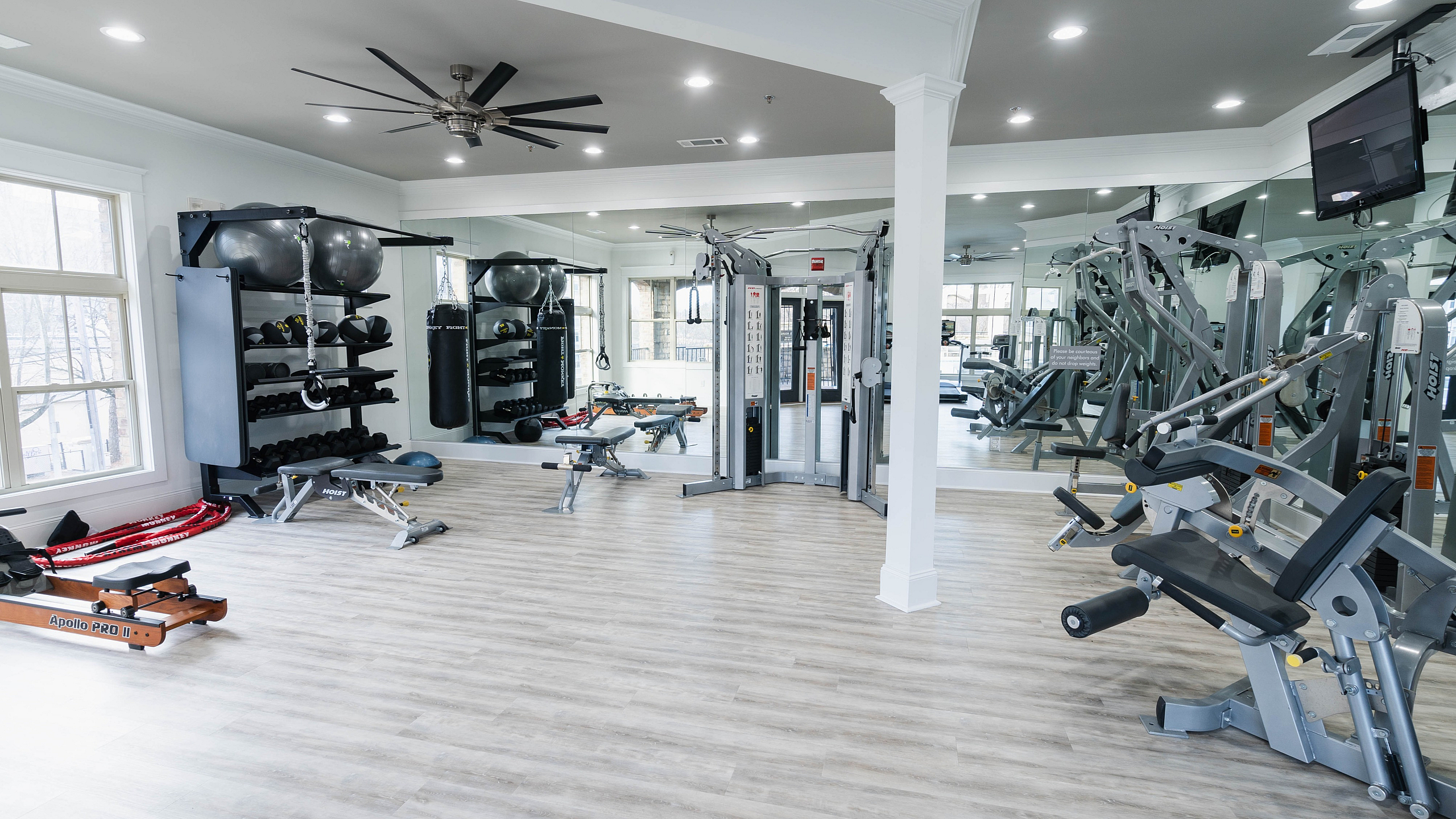 Modern fitness center with state-of-the-art gym equipment, mirrored wall, and bright windows.