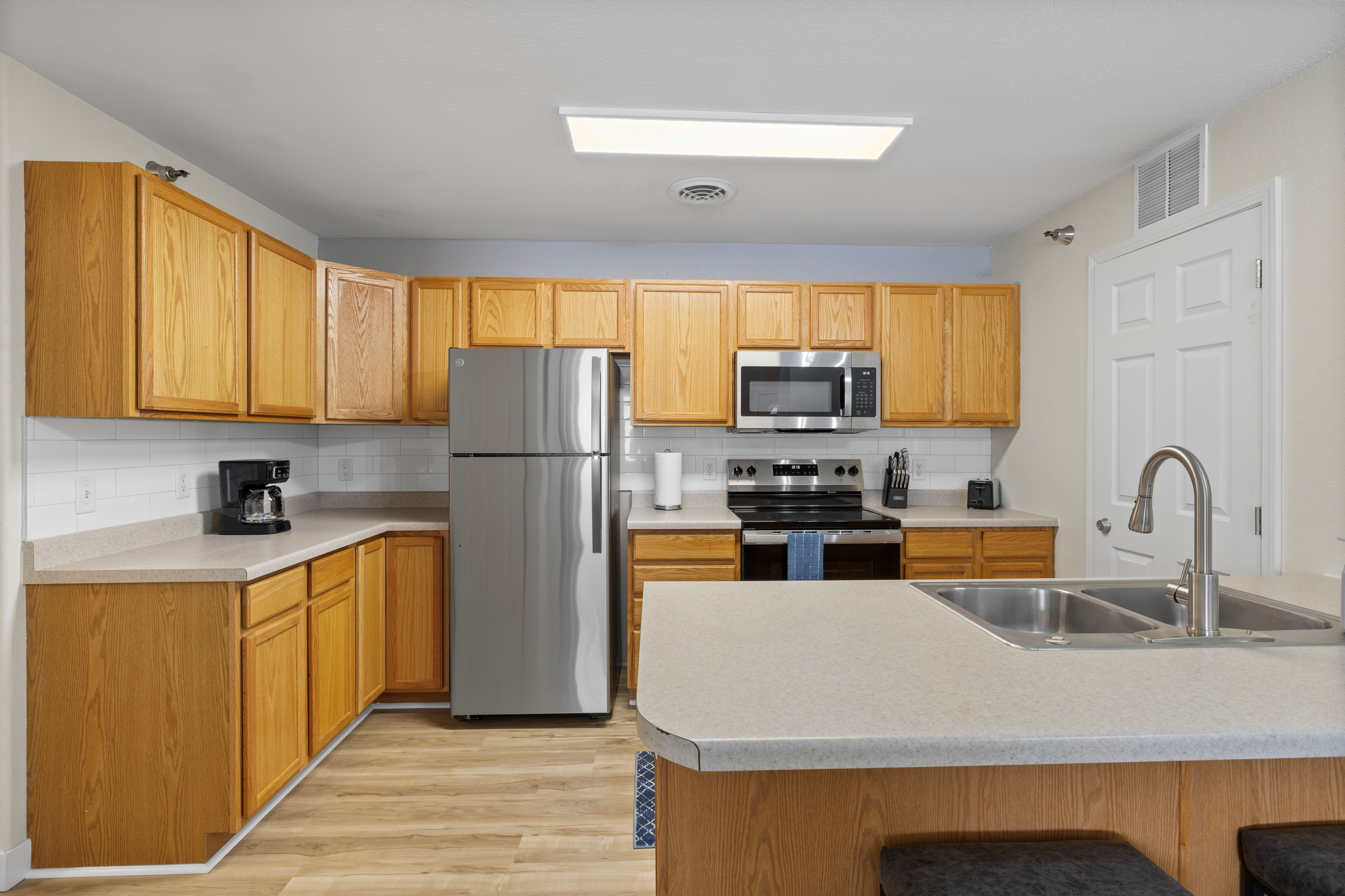 Modern kitchen with elegant wooden cabinetry, stainless steel appliances, and sleek countertops enhanced by natural lighting.