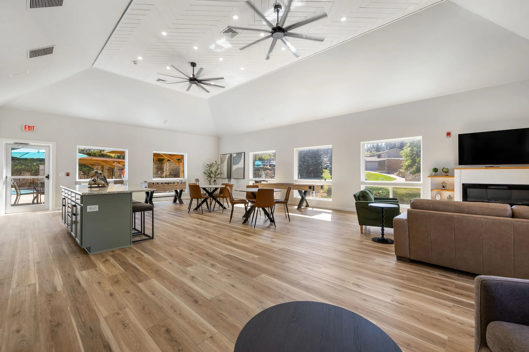 Contemporary open-plan living space with elegant hardwood floors, modern ceiling fans, bright natural lighting, and a stylish seating area with a fireplace.
