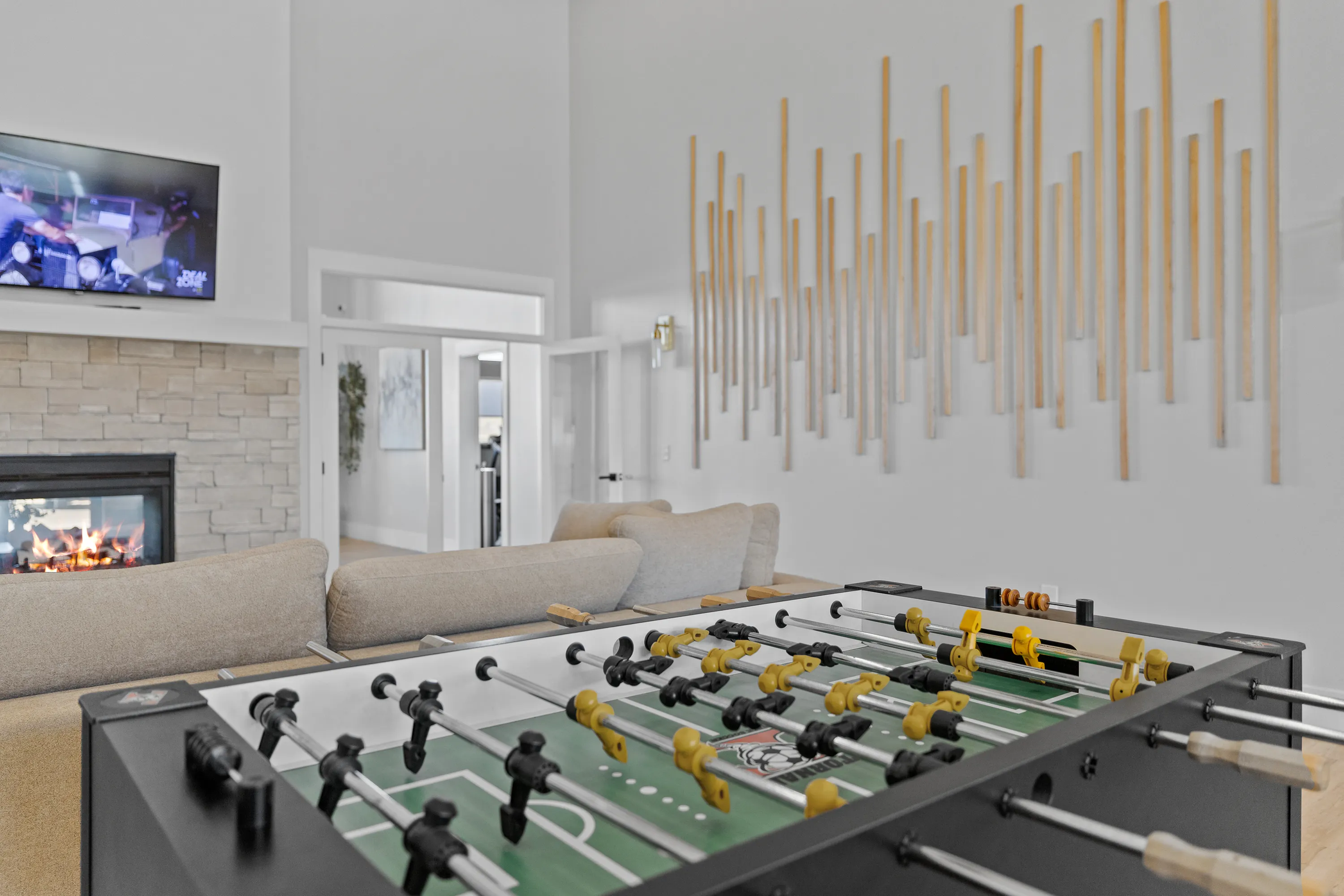 Modern living room featuring a cozy stone fireplace, stylish wall art, and a fun foosball table.