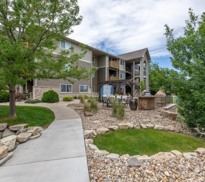 Charming apartment complex with lush landscaping, inviting outdoor seating, and modern architecture.