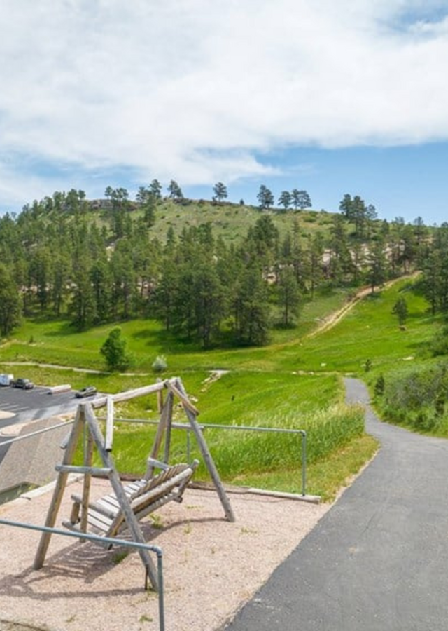 Breathtaking hillside view with a rustic wooden swing overlooking lush green landscape and winding pathways.