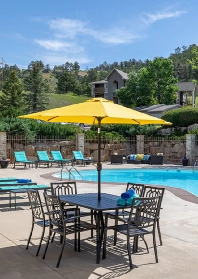 Charming poolside oasis featuring bright yellow umbrellas, stylish lounge chairs, and lush greenery, perfect for relaxation.