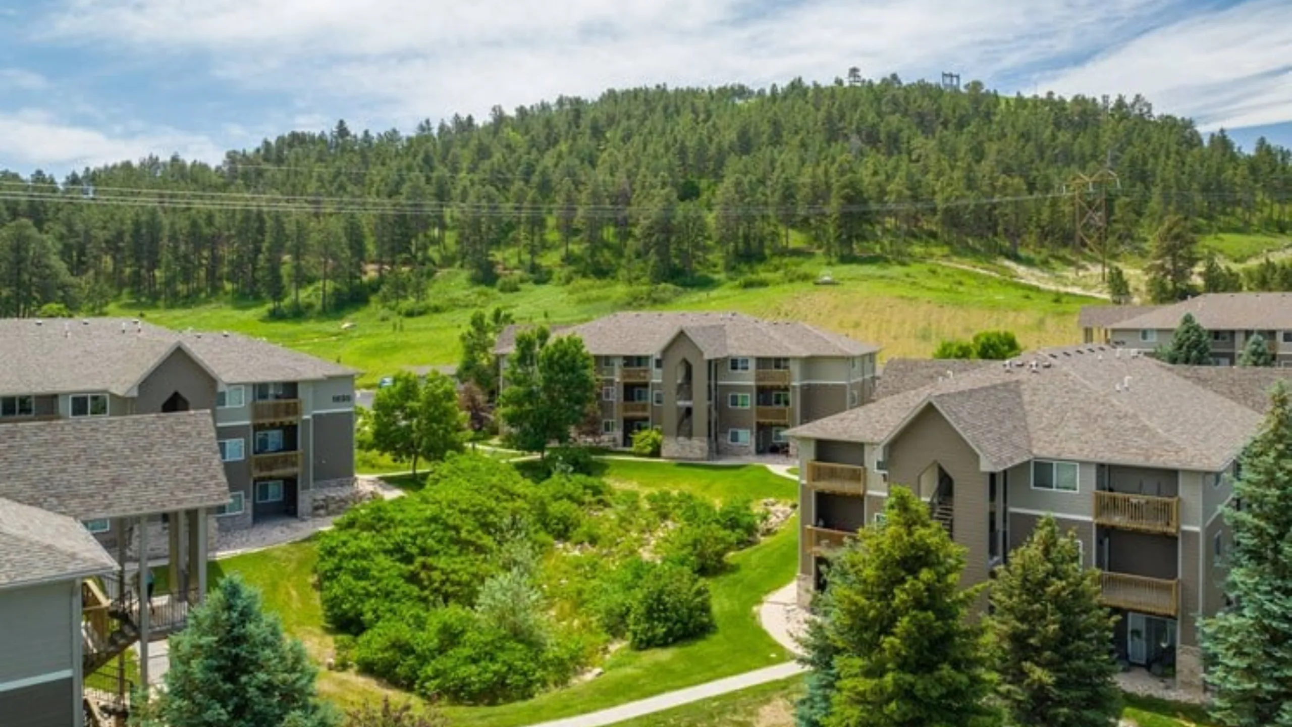 Charming apartment complex nestled in lush greenery with scenic hillside views and modern architecture.