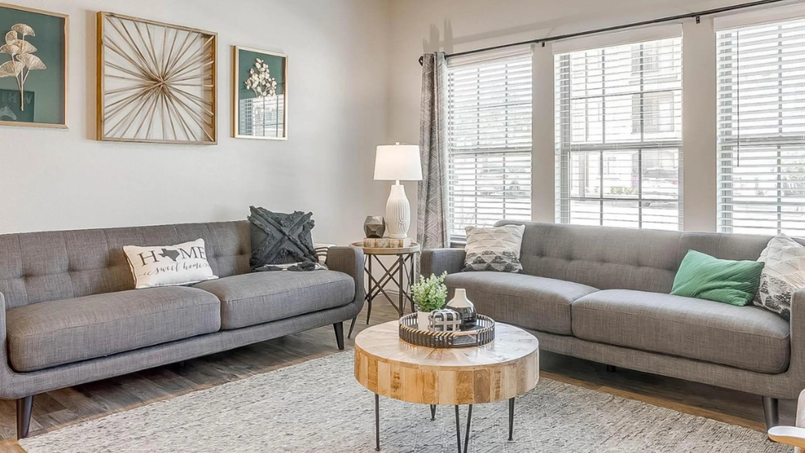 Bright and inviting living room with modern gray sofas, stylish decor, and sunlit windows creating a warm, welcoming ambiance.