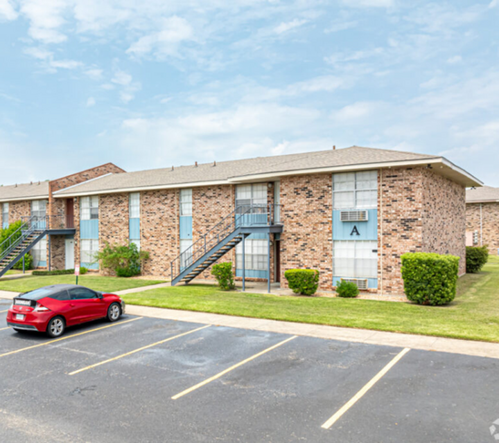 Charming brick apartment complex with modern exterior, manicured lawns, and convenient parking.