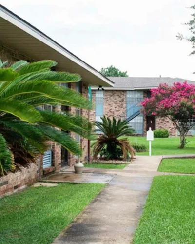 Charming apartment complex surrounded by lush greenery and vibrant flowering trees, offering a serene outdoor environment.