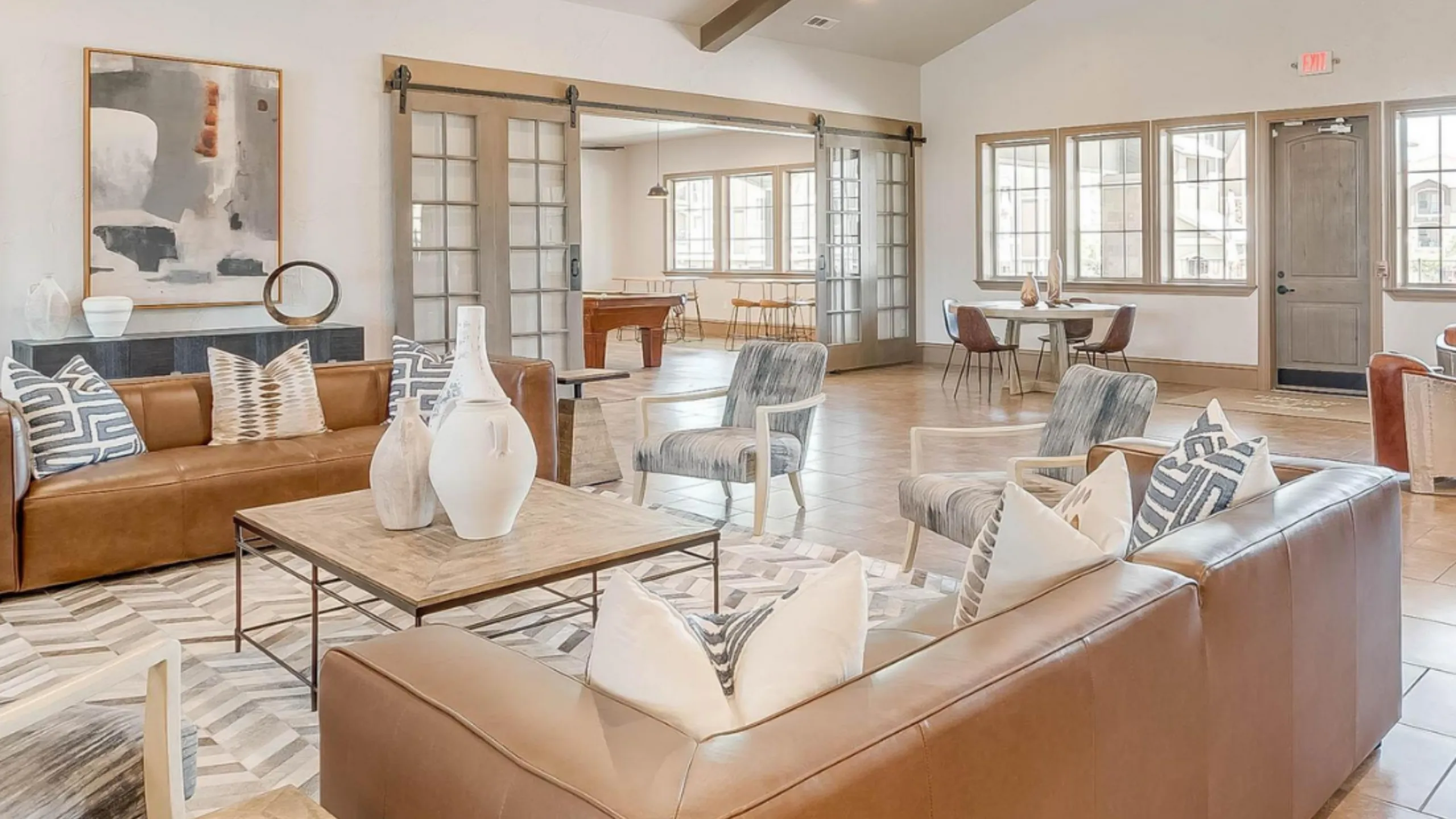 Luxurious communal lounge with elegant leather sofas, chic decor, and natural light, perfect for relaxation and social gatherings.