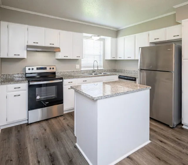Modern kitchen with granite countertops, sleek stainless steel appliances, and elegant white cabinetry, offering a bright and inviting cooking space.