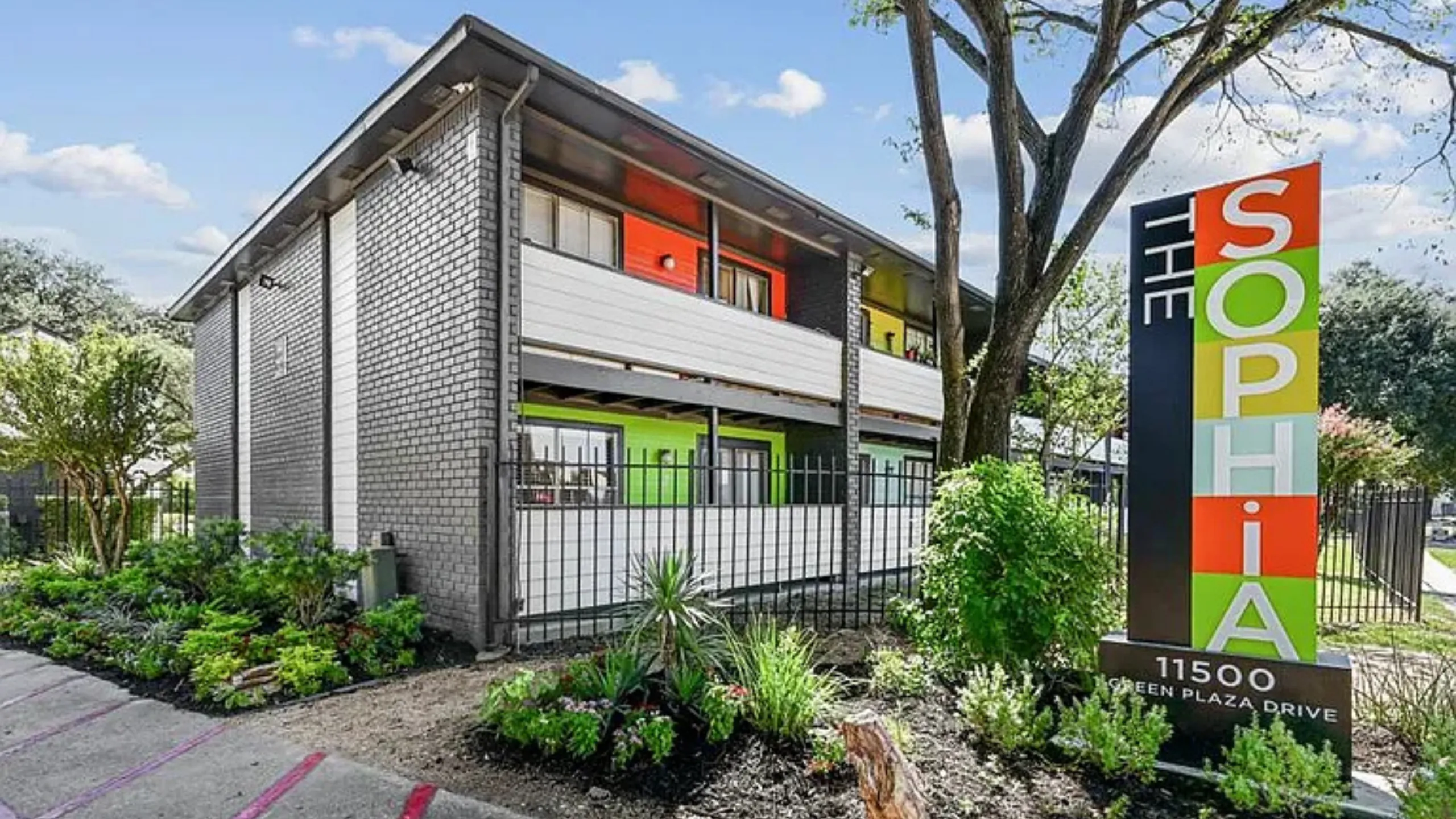 Chic urban apartment exterior with vibrant colors and lush landscaping at The Sophia.