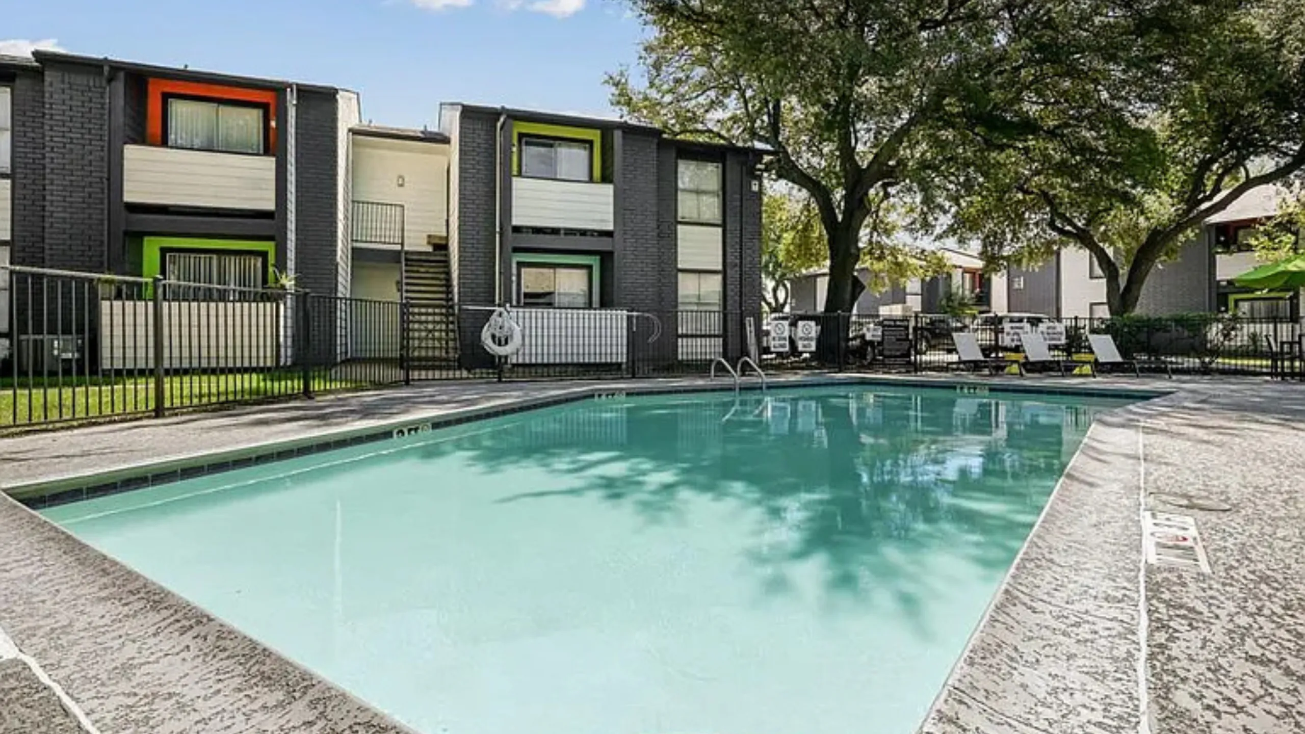 Inviting apartment complex with a refreshing outdoor swimming pool, surrounded by lush greenery and modern architecture.