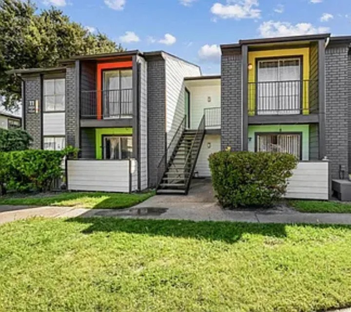 Charming two-story apartment complex with bright accents, cozy balconies, and lush greenery, perfect for vibrant living.