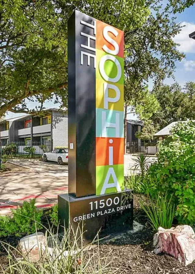 Vibrant signage of The Sophia apartment community at 11500 Green Plaza Drive, showcasing modern and inviting design amidst lush greenery.