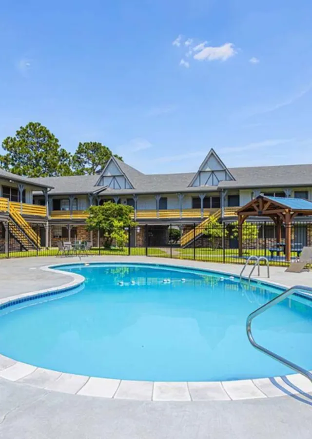 Charming apartment complex with a serene pool and lush greenery, perfect for relaxation and leisure.